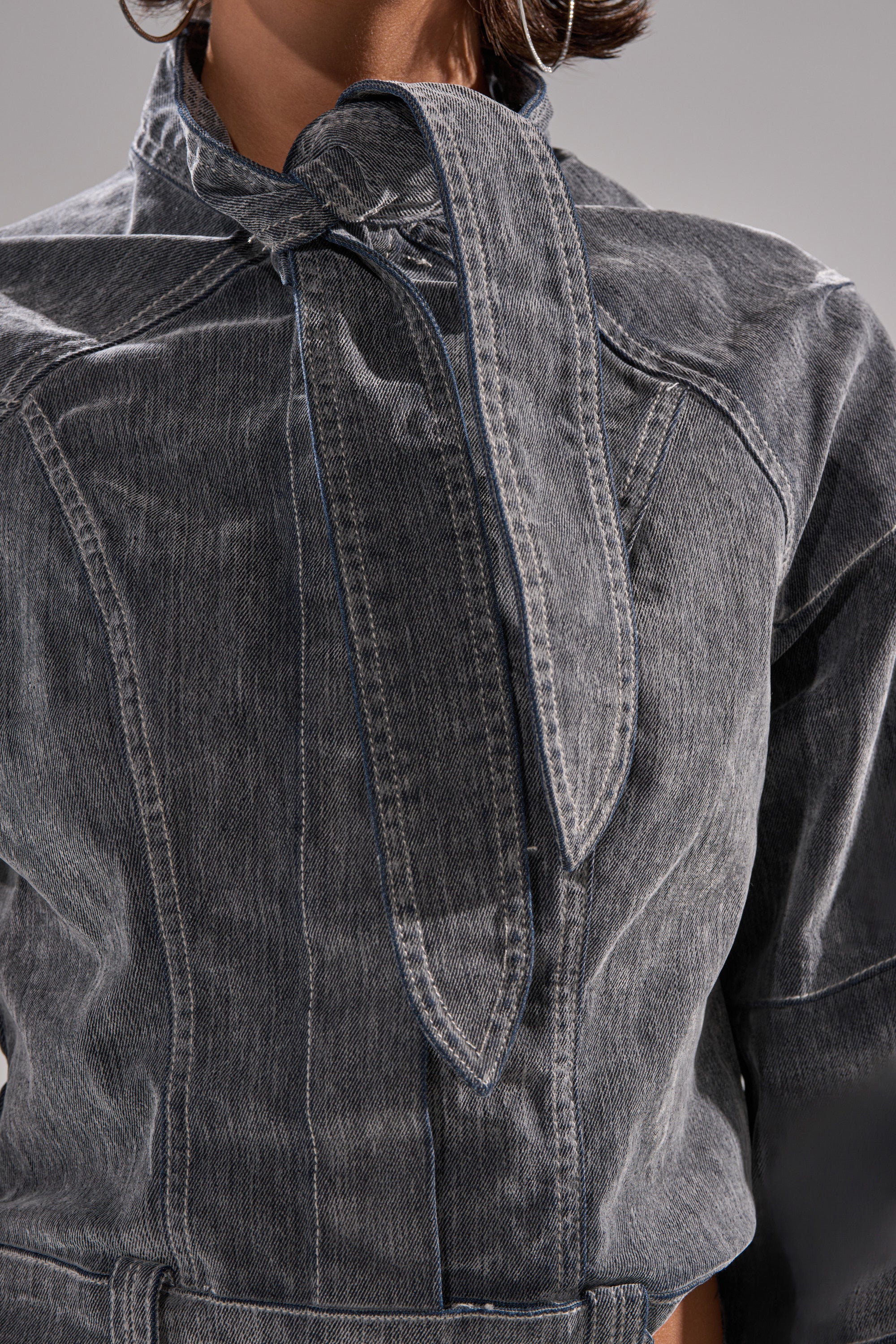 Close-up of a person wearing the CATCHING EYES VELVET DENIM BLOUSE, featuring gray velvet denim, a large pointed collar tied at the high neckline, cropped fit, visible stitching, and a slightly faded look.