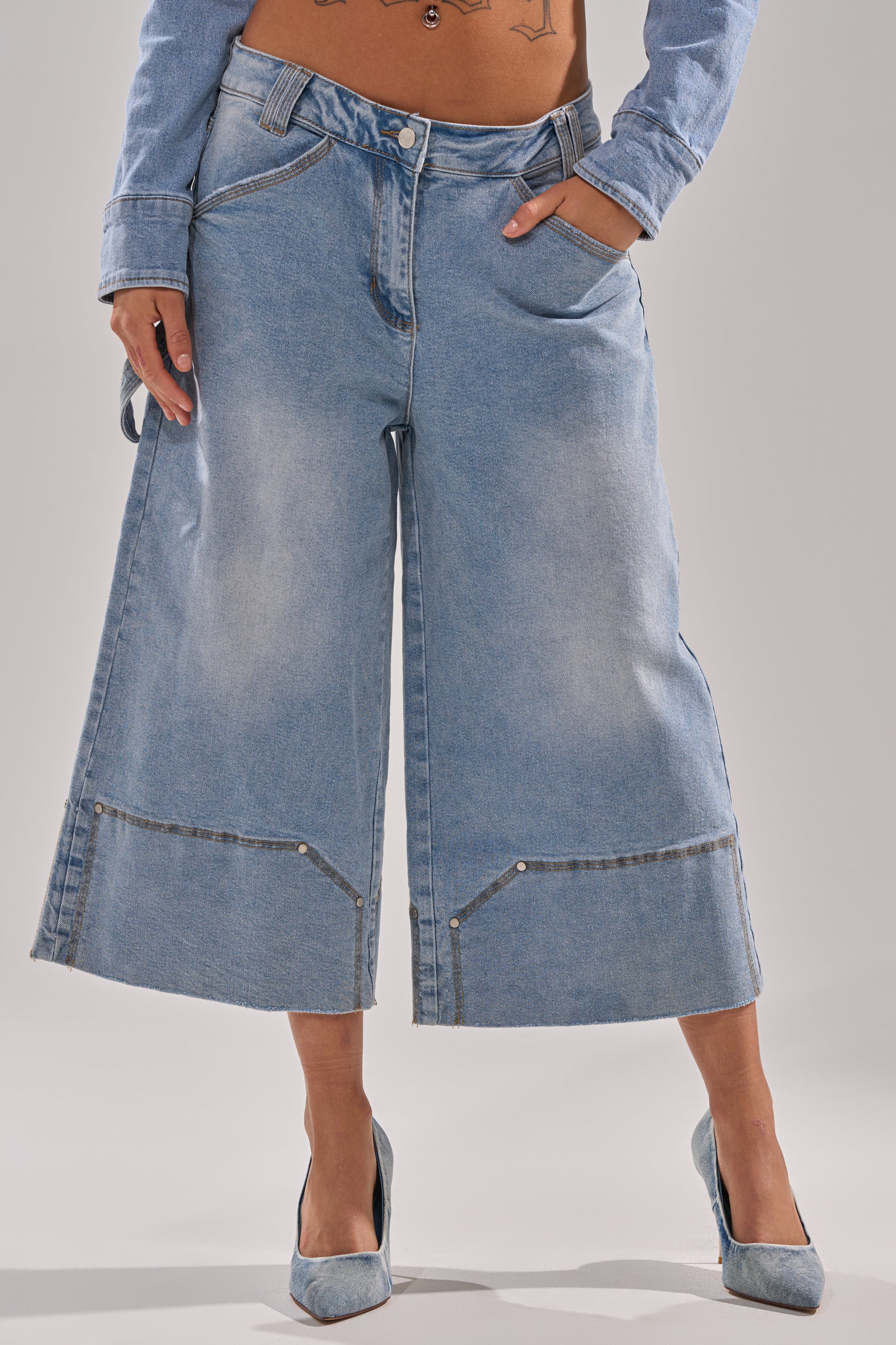 A person wearing ROCK MY WORLD WIDE-LEG DENIM BERMUDA SHORTS in light blue with decorative hem stitching and a relaxed fit, paired with blue heels and a partially visible denim jacket.