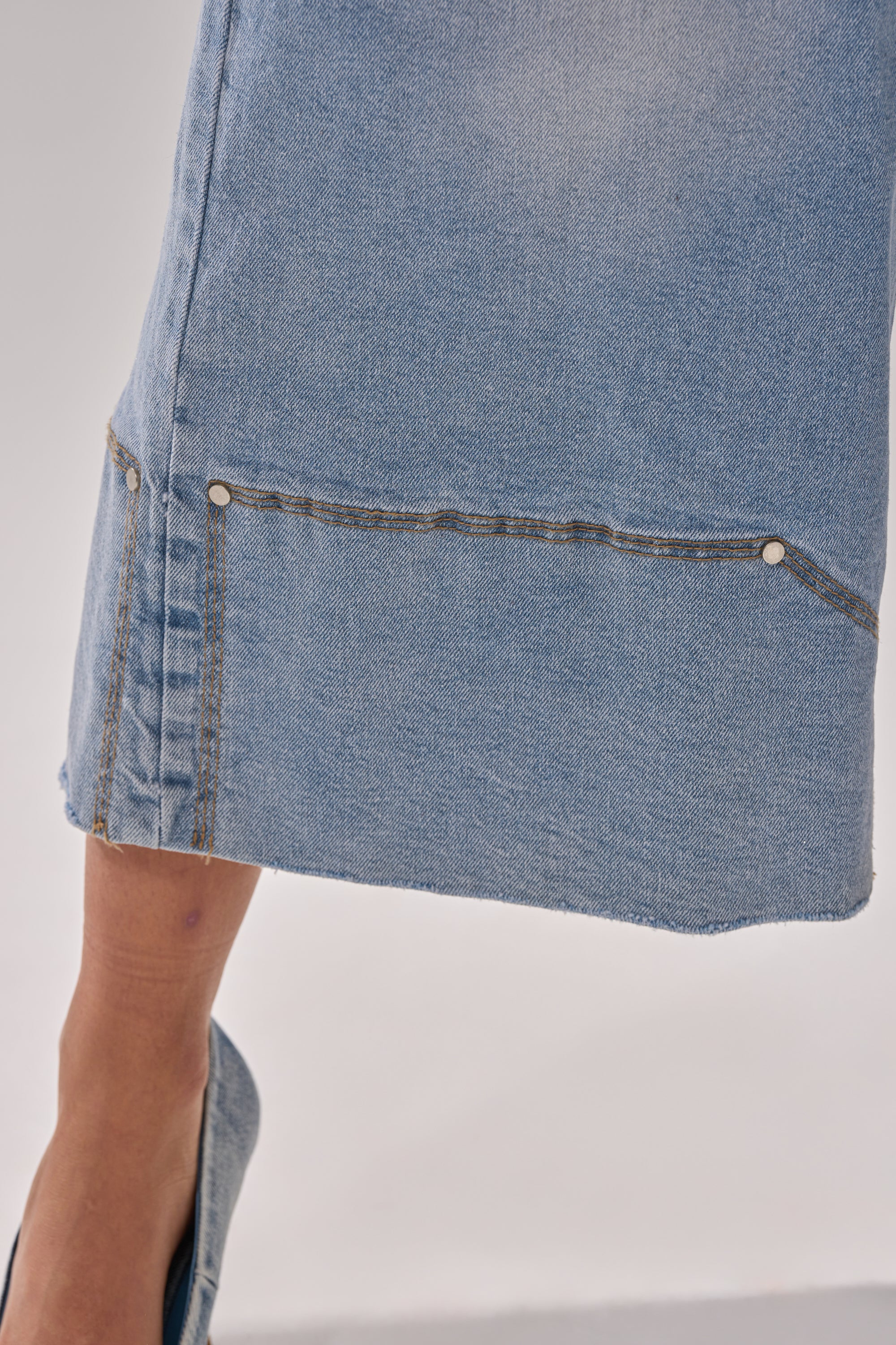 Close-up of the lower leg wearing ROCK MY WORLD WIDE-LEG DENIM BERMUDA SHORTS, featuring visible seams and rivets, styled with a matching denim shoe. The background is plain and light-colored.
