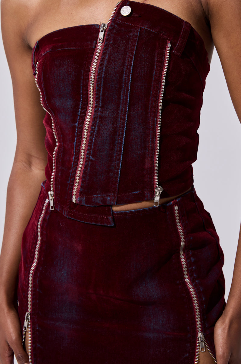 Wearing the ASYMMETRIC ZIP CORSET in strapless burgundy velvet with bold silver zippers, styled with a matching skirt, creates a modern and edgy statement look. 6