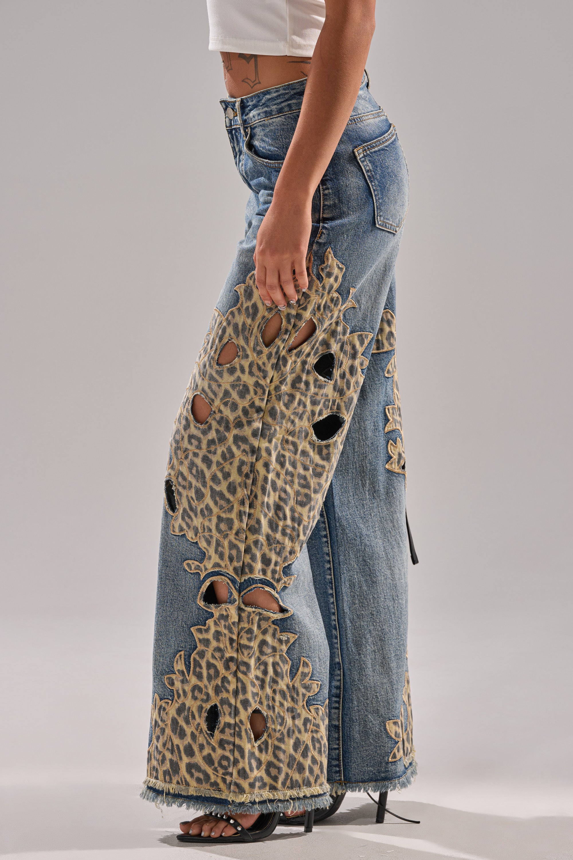 A woman wears the AMIGAS CHEETAH PRINT WIDE LEG PANT with a white crop top and black heeled sandals, standing against a neutral background.