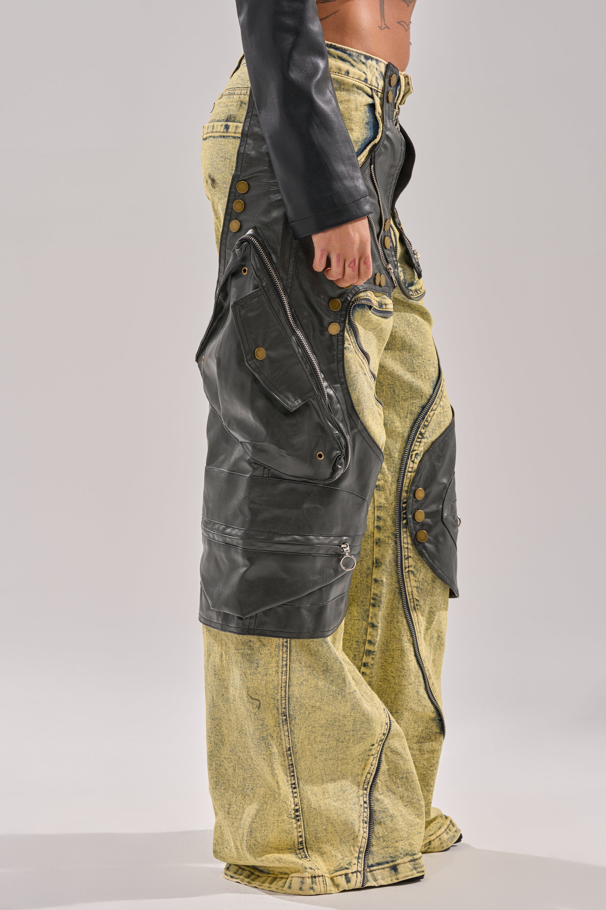 A person wearing CRAZY FOR YOU RELAXED DENIM wide-leg acid-wash jeans with oversized faux leather paneling and brass buttons, shown from the waist down against a plain light background. 5
