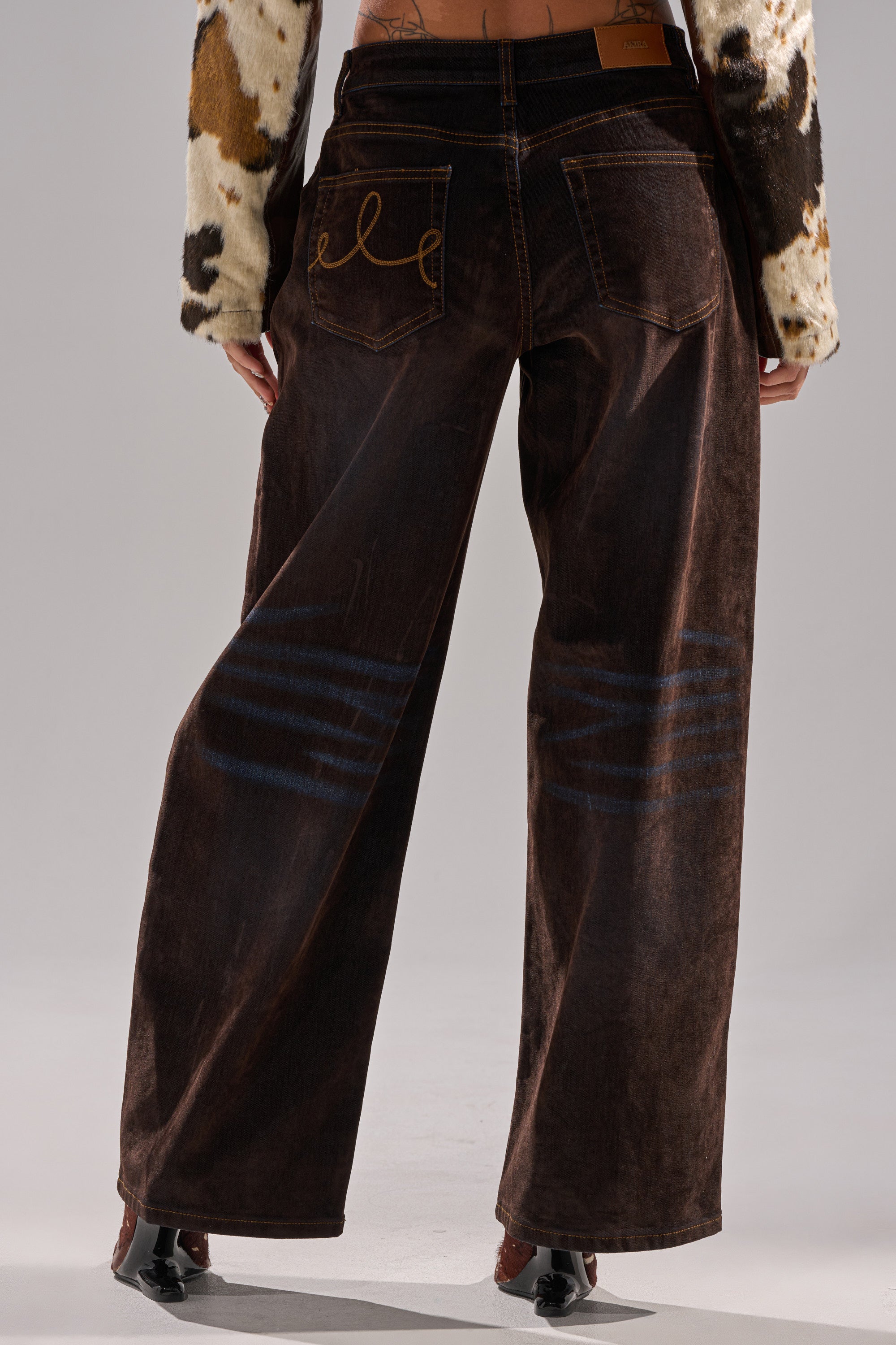 Wearing DAYLIGHT VELVET DENIM wide-leg dark brown corduroy pants with orange stitching and faded blue circles, paired with a cropped cow-print sweater—a stylish, jean-inspired look.