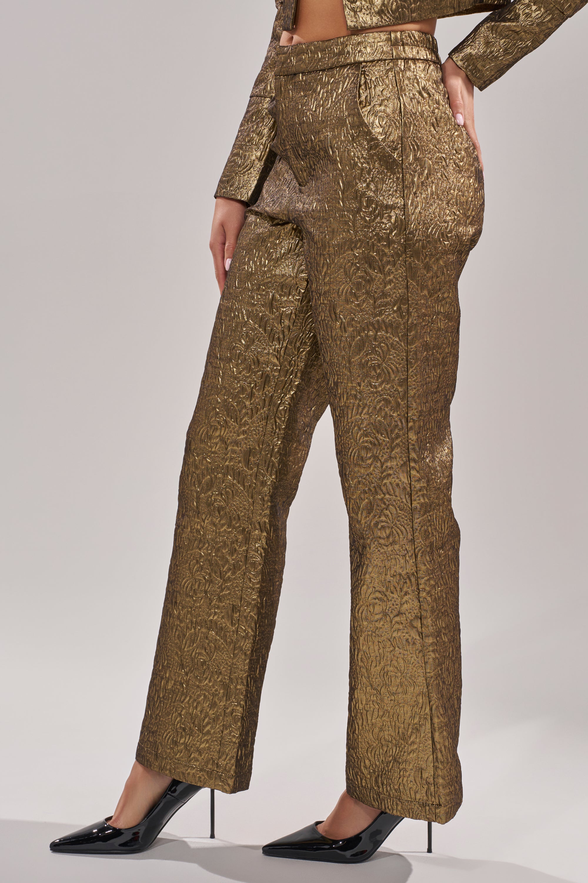 Wearing the DAPHNE BROCADE TROUSER with a matching gold jacket and black pointed-toe heels, a person stands against a plain light background. 1