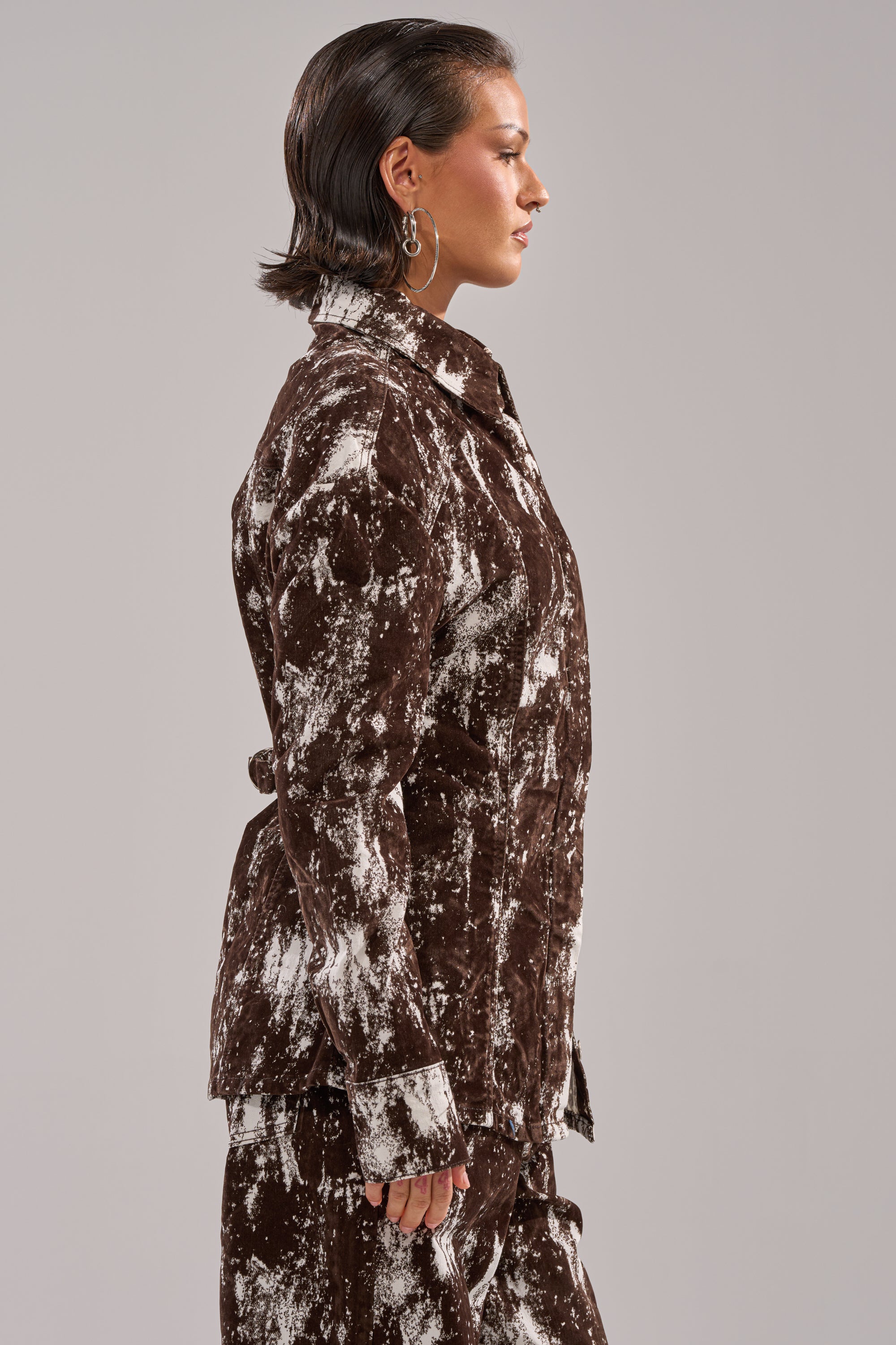 Wearing the CRAZY IN LOVE BUTTON DOWN and matching pants in a brown and white abstract print, a person with short, slicked-back hair is shown in profile against a plain light gray background. 2