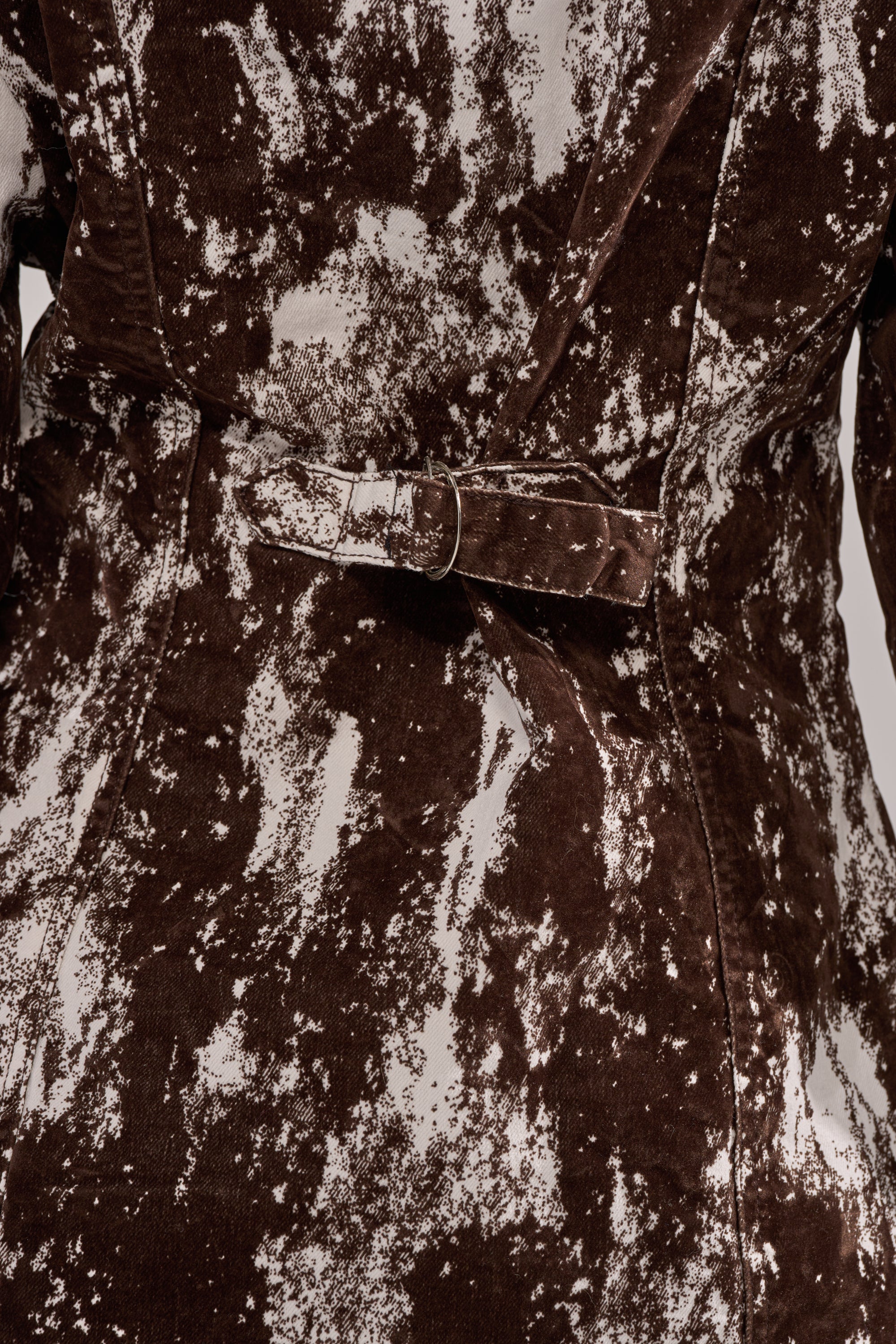Close-up of the back of a brown and white patterned coat with a fabric belt and visible stitching, paired with the CRAZY IN LOVE BUTTON DOWN for added contrast. 7