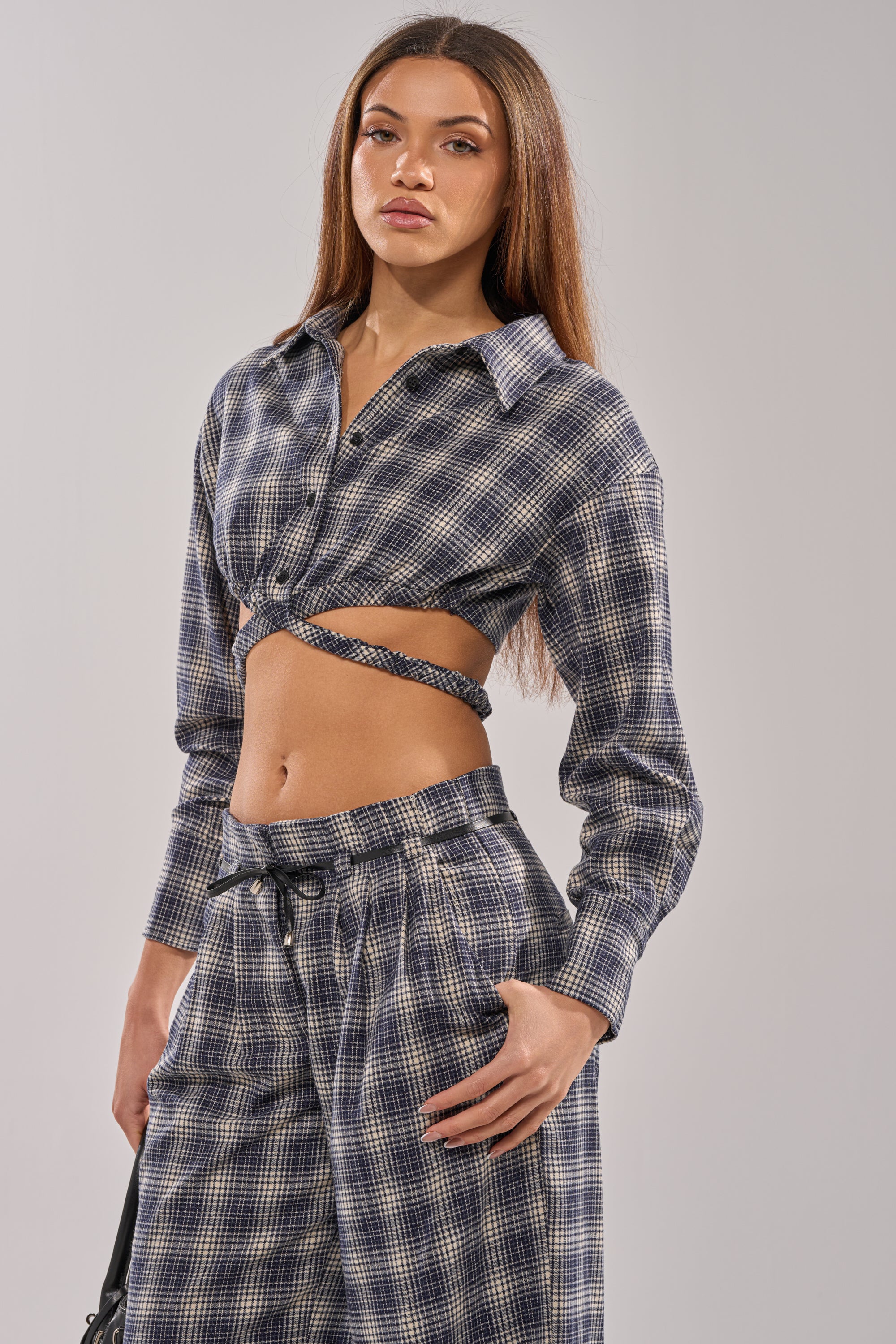 A woman with long straight hair wears the JANE PLAID BUTTON DOWN in blue and white, paired with matching high-waisted pants, standing against a plain light background.
