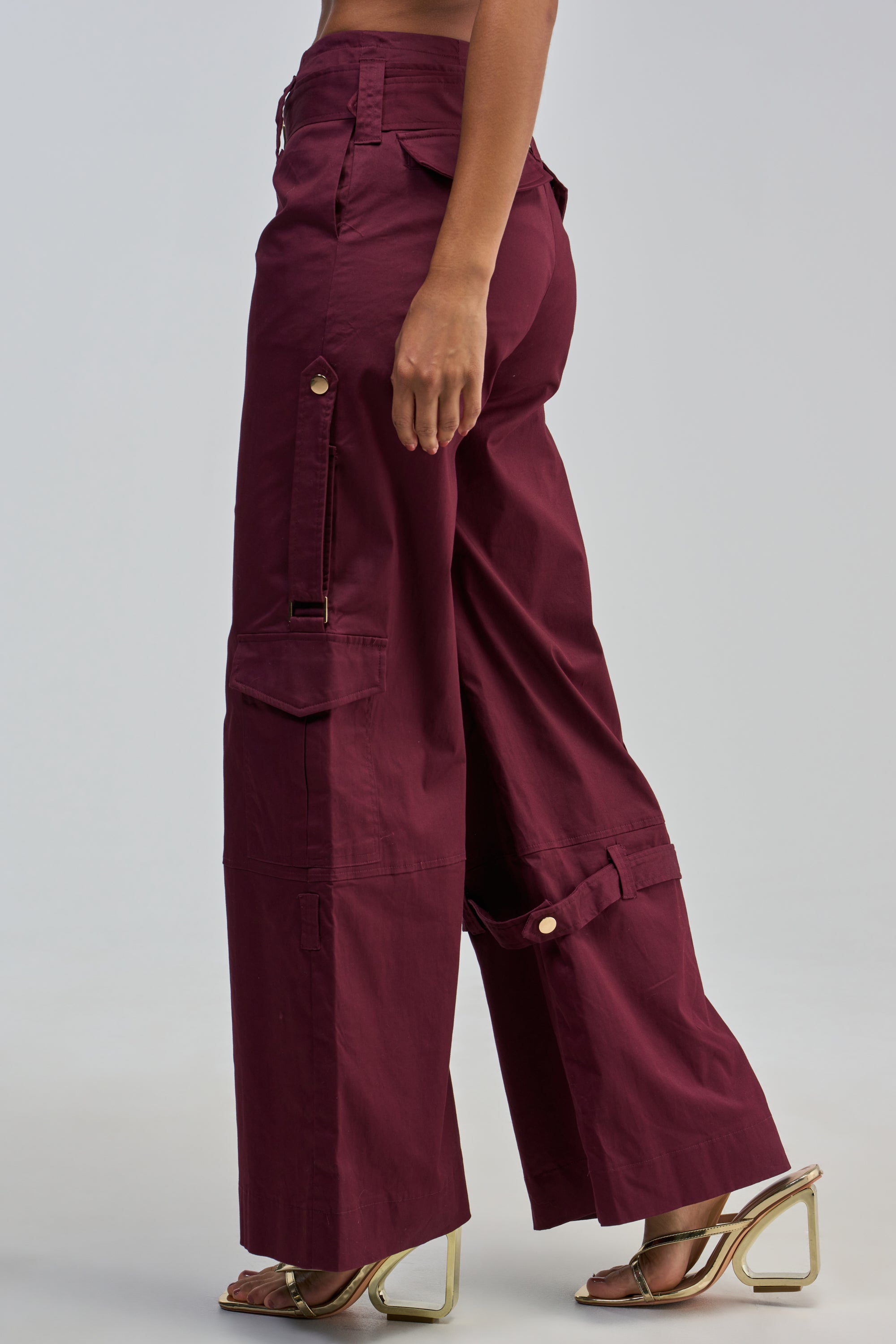 A person wearing the FLORENCE PLUM TROUSER, featuring a wide-leg silhouette, paired with gold open-toe high heel sandals, poses against a plain light background.