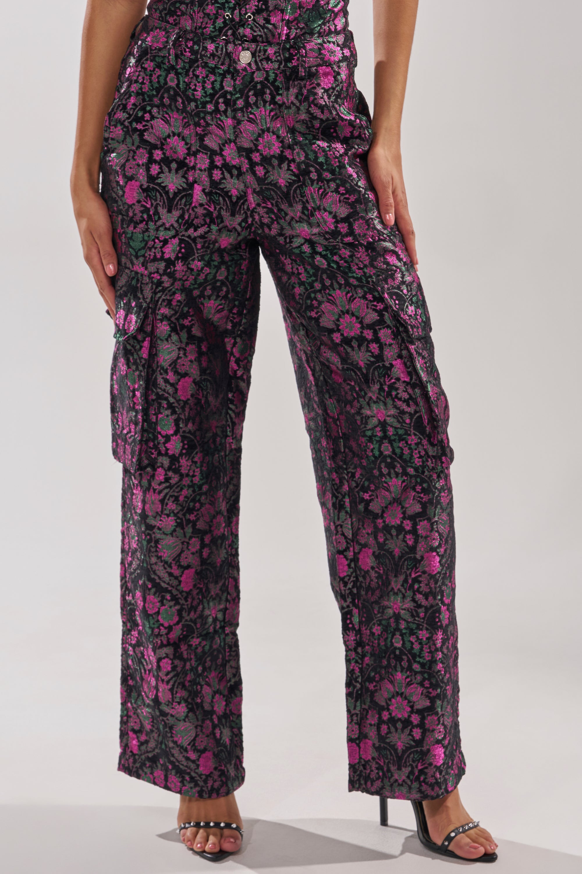 Wearing the KIMMY FLORAL TROUSER—high-rise with a pink and black floral pattern—paired with black high-heeled sandals. The photo is cropped at the waist and ankles. 3