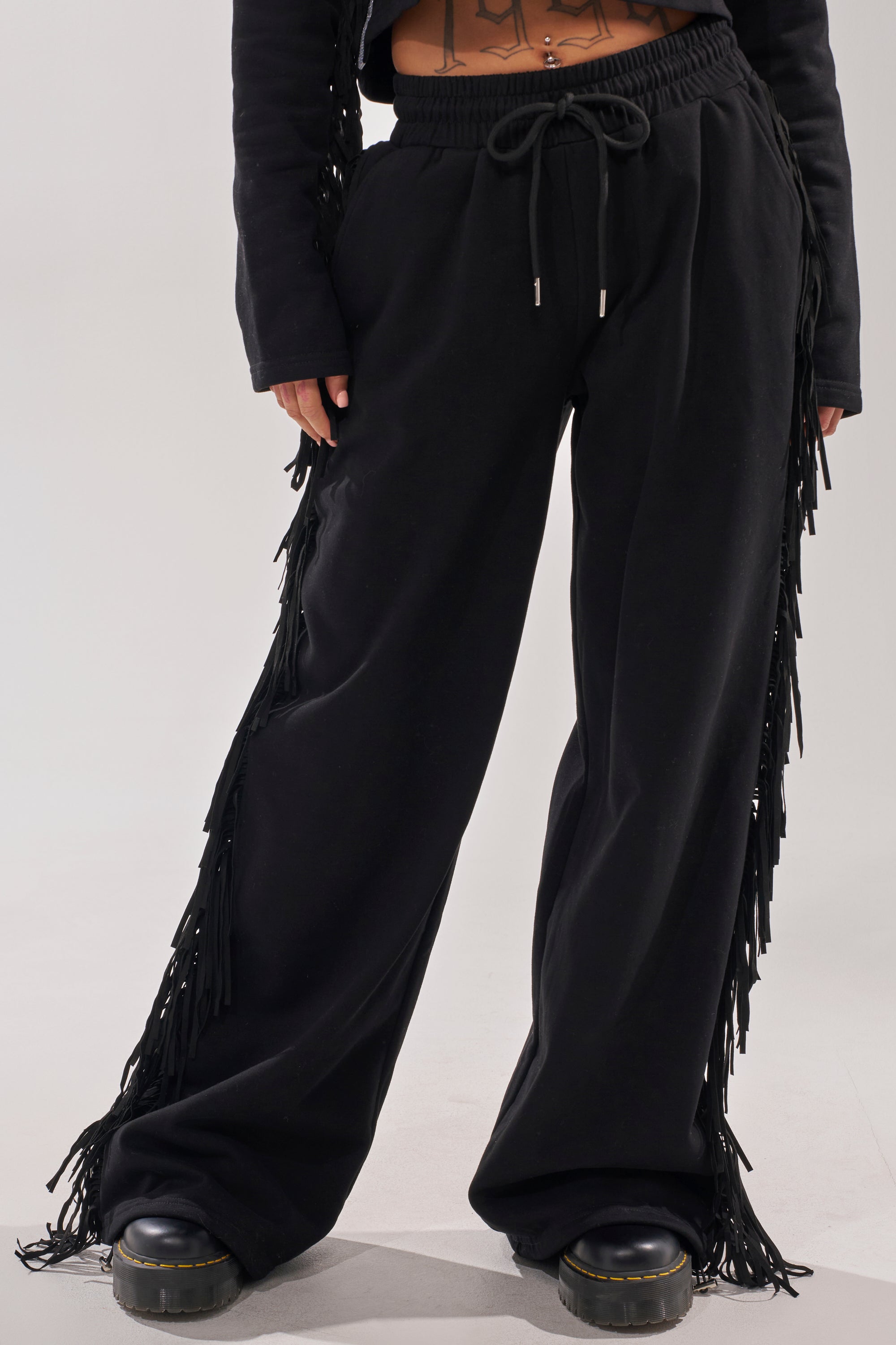 A person wearing the PLAYING CARDS WIDE LEG JOGGER in black with platform shoes, standing against a plain light background. Only the lower body is shown. 2