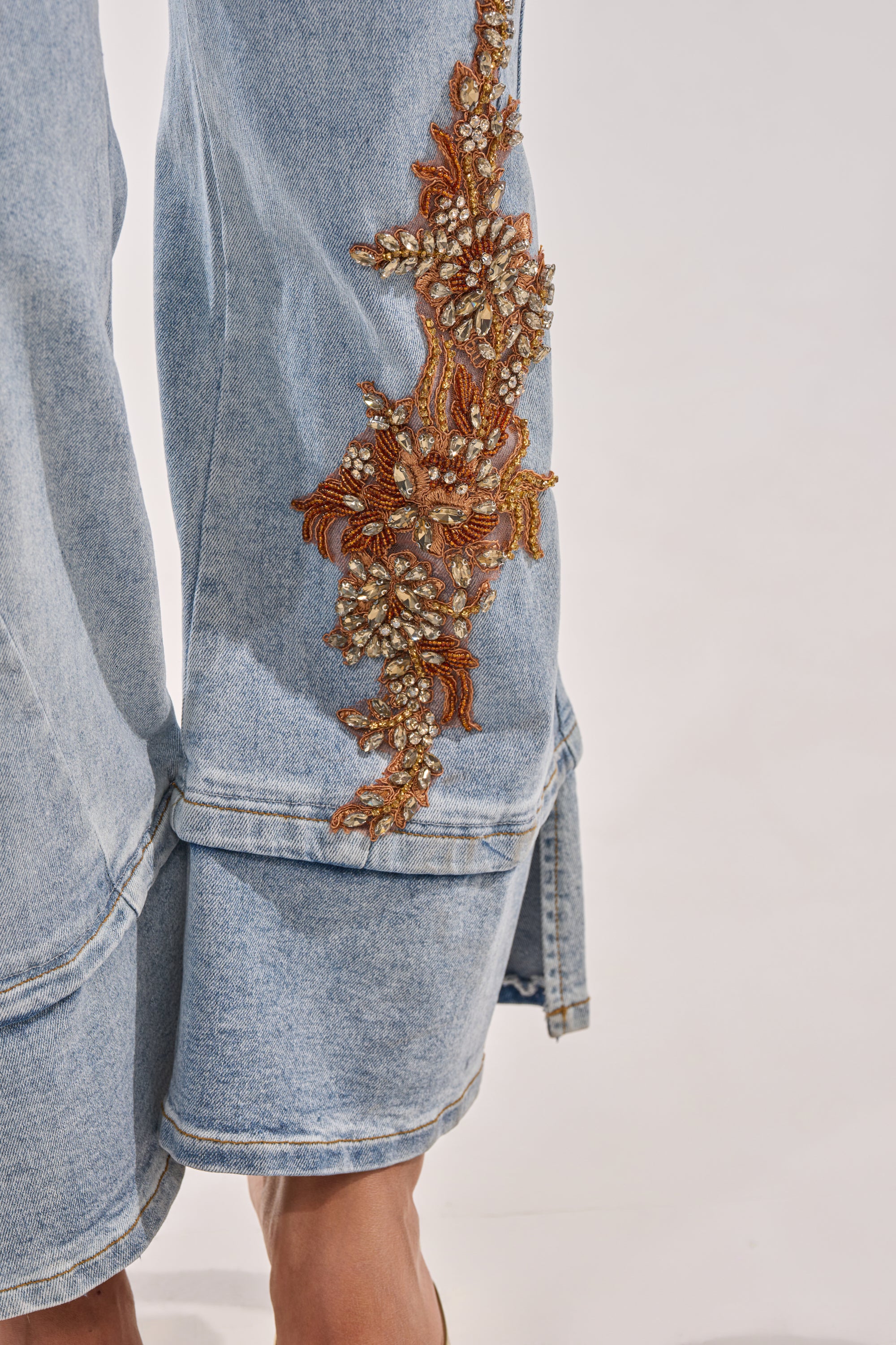 Close-up of TOTALLY COOL RELAXED DENIM in light blue, featuring intricate gold and amber beaded embroidery on the side, shown against a plain background. 7
