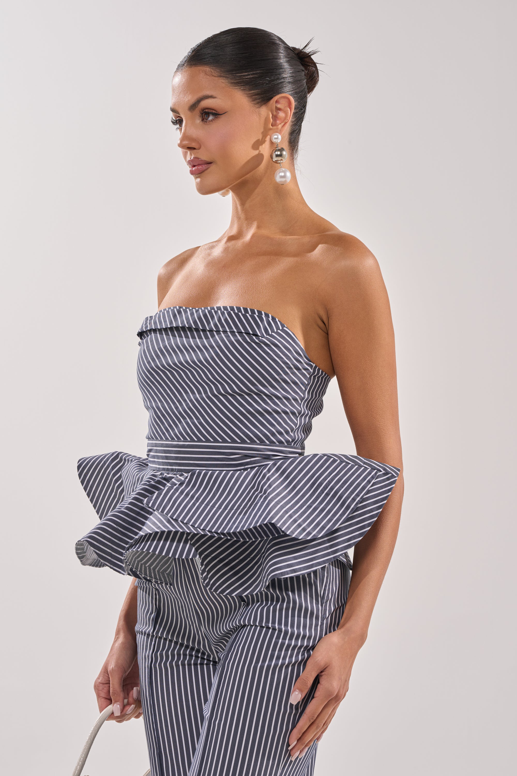 A woman wears the MISS POPULAR POPLIN CORSET in black-and-white pinstripes with matching pants, styled with large drop earrings and a sleek bun. 2