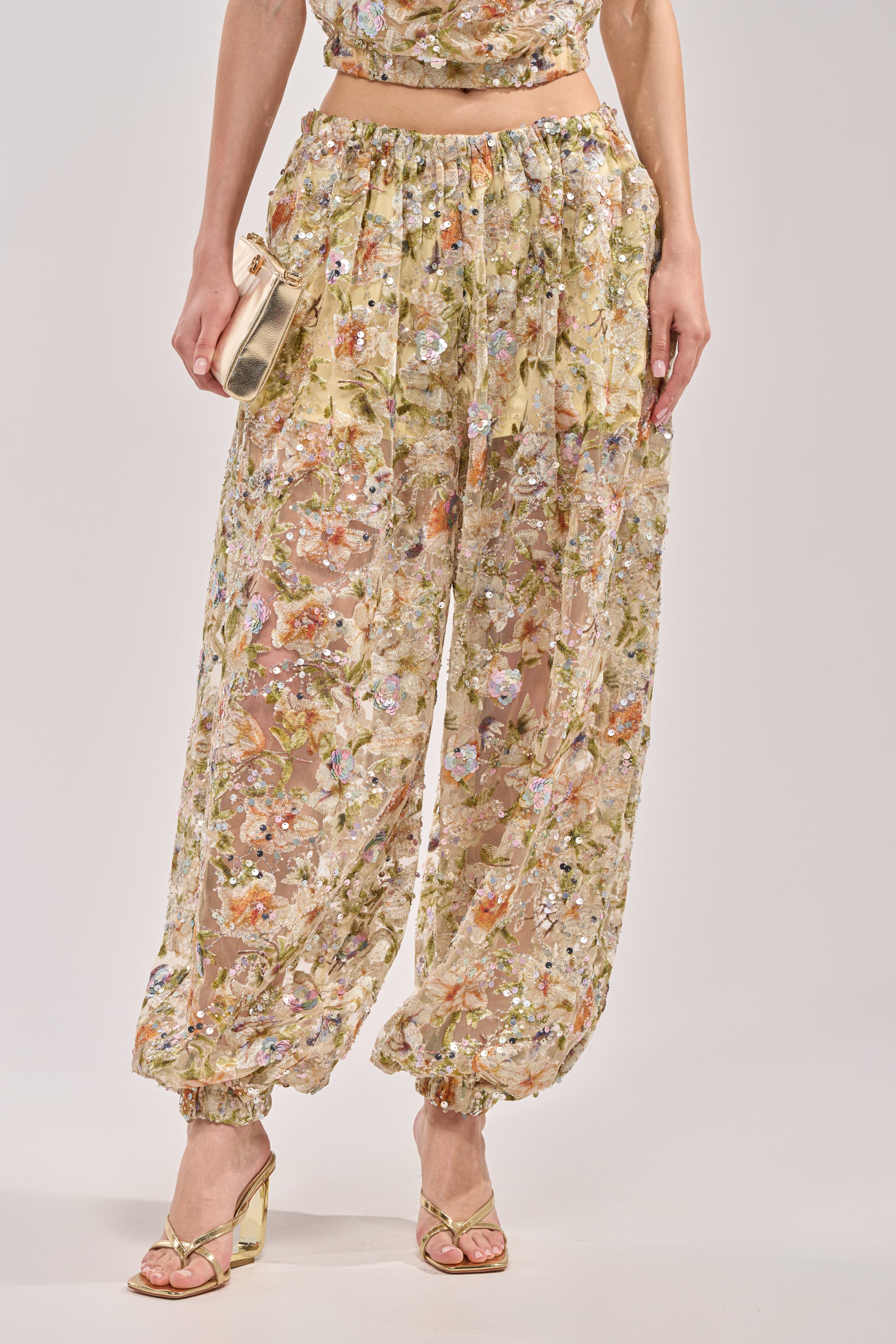 Wearing the LETS TALK ABOUT IT BALLOON PANT with floral embroidery, gathered ankles, gold heeled sandals, and a gold clutch, they create a delicate and effortlessly chic light-toned look. 1
