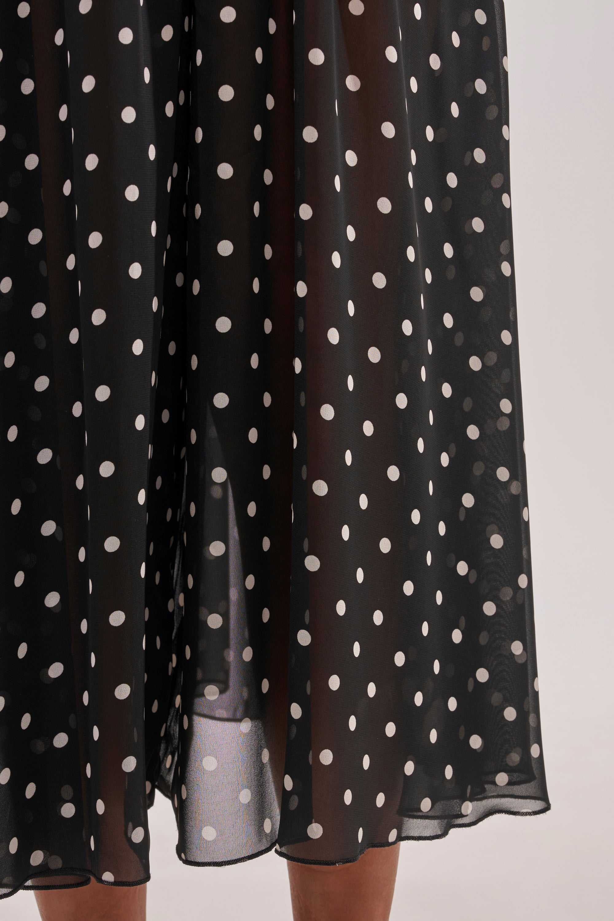 Close-up of a person wearing COOL GIRL POLKA DOT GAUCHO PANT—black chiffon pants with white polka dots, shown from the lower legs. 7