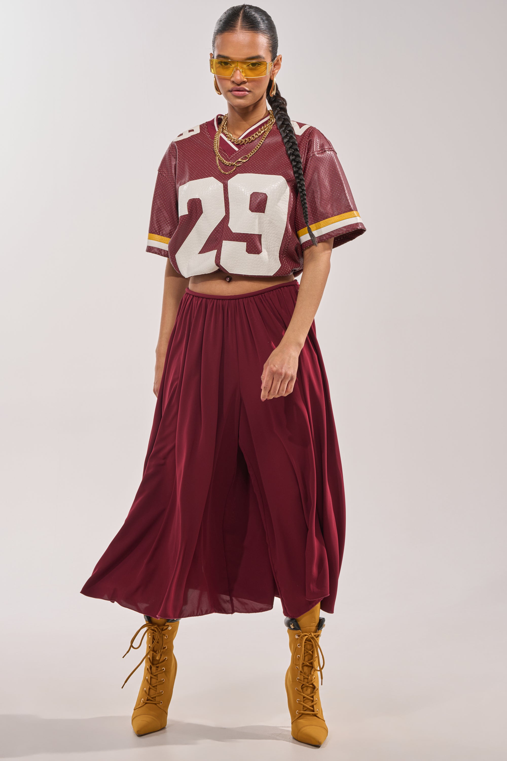 A woman poses confidently in yellow sunglasses, a maroon football jersey with the number 29, COOL GIRL GAUCHO PANT featuring a wide-leg silhouette, and yellow lace-up boots against a plain background. 6