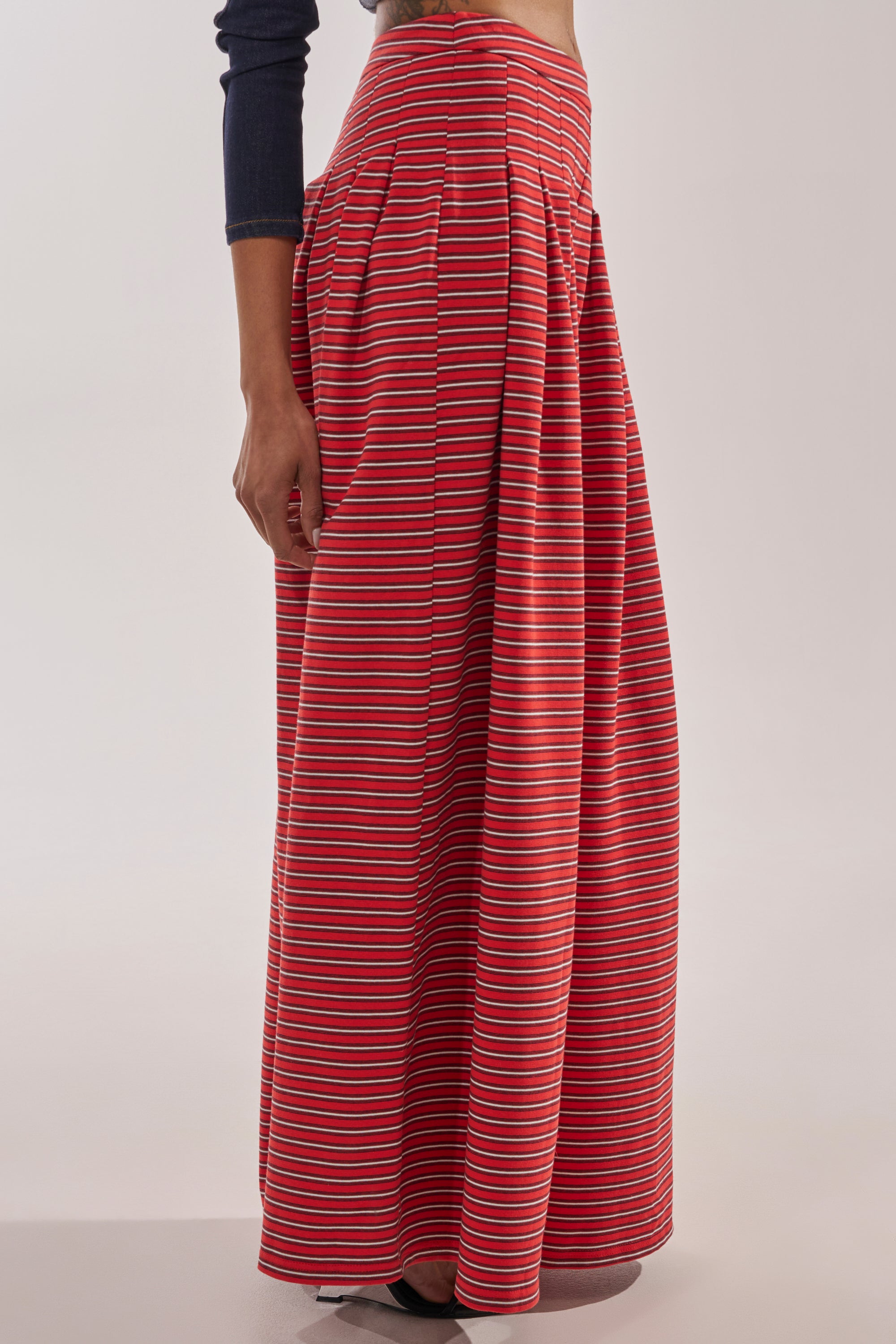 A person wearing the SILVER COAST STRIPE TROUSER, featuring a high-waisted design with horizontal white and blue stripes, stands sideways against a plain light background. 3
