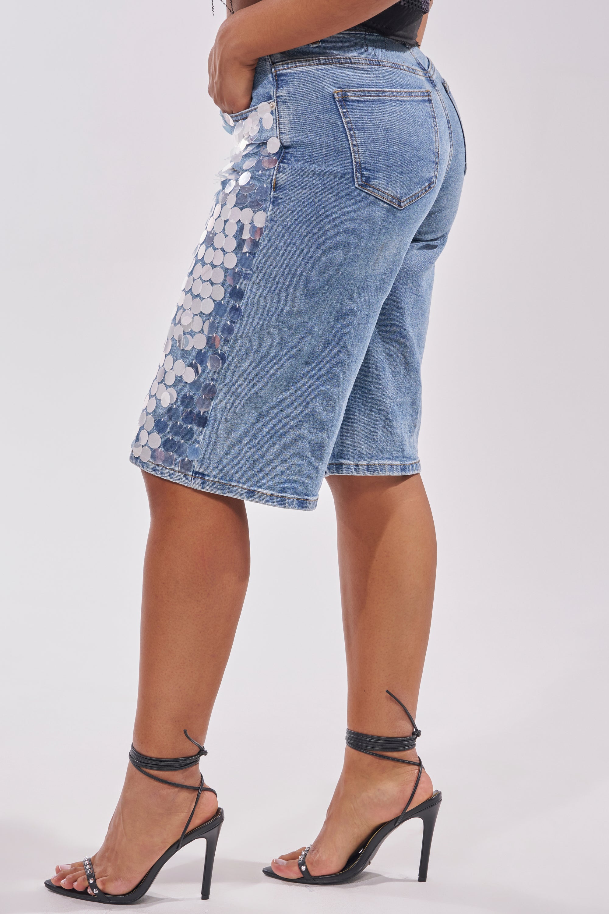 Wearing the SPARKLE AND SHINE BERMUDA SHORT with eye-catching silver sequins and black strappy high-heeled sandals, this look embraces bold festival style against a simple backdrop. 3