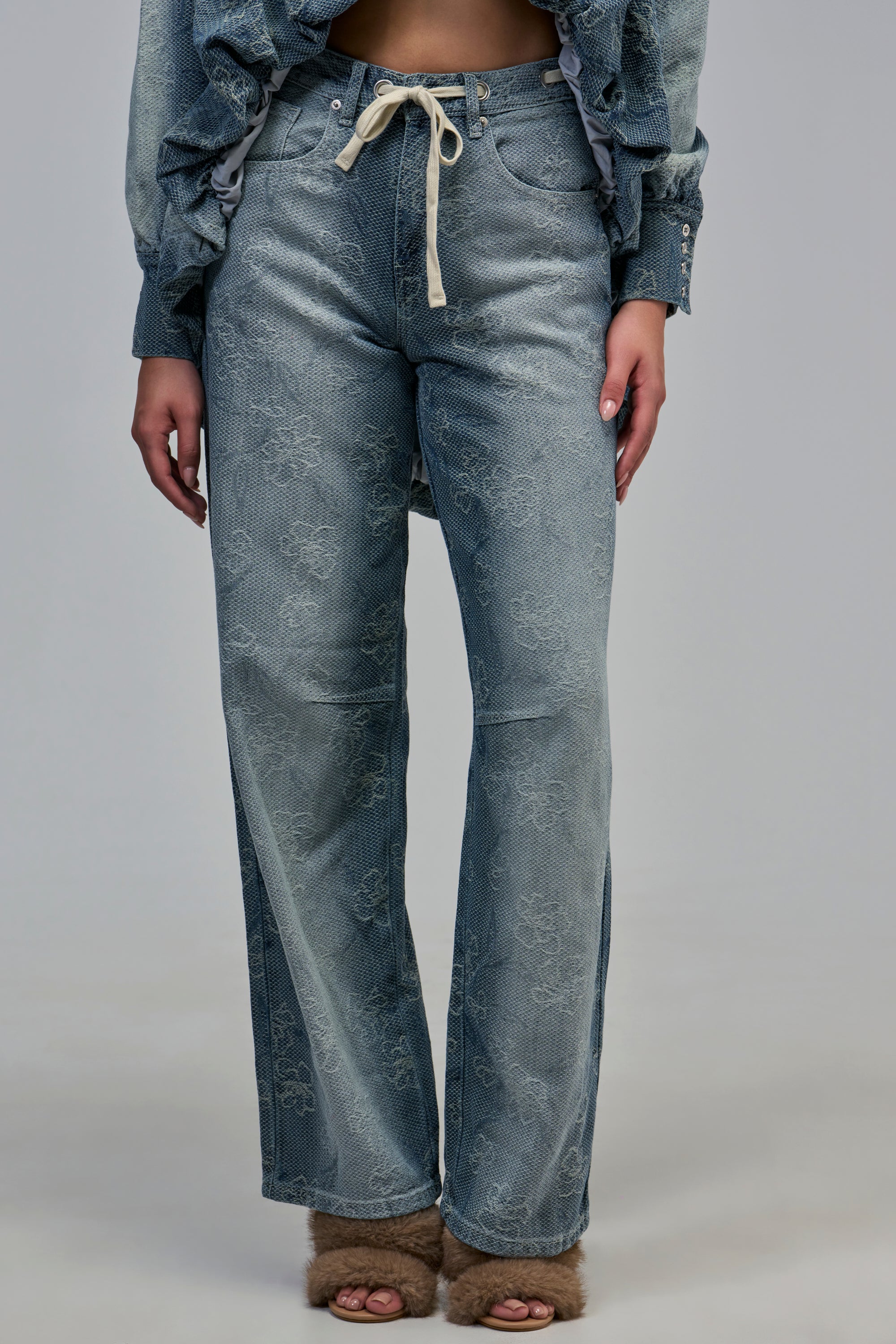 ALICE EMBROIDERED DENIM wide-leg light wash jeans with faint floral embroidery and a white drawstring waist.