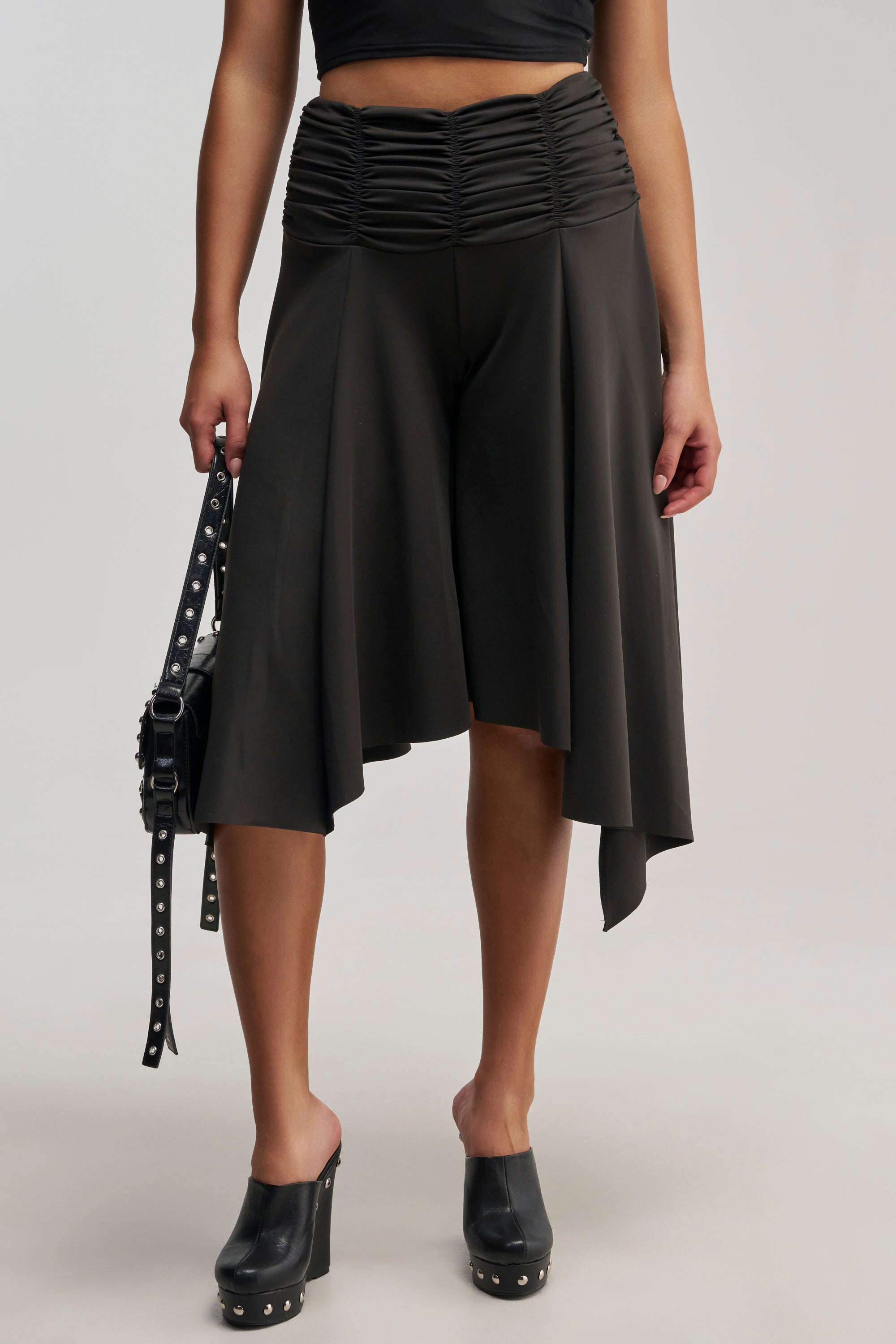 Wearing the FLYING AWAY GAUCHO, black clogs, and carrying a black studded bag, this person perfectly captures the elegance often seen in minimalist pants styles.