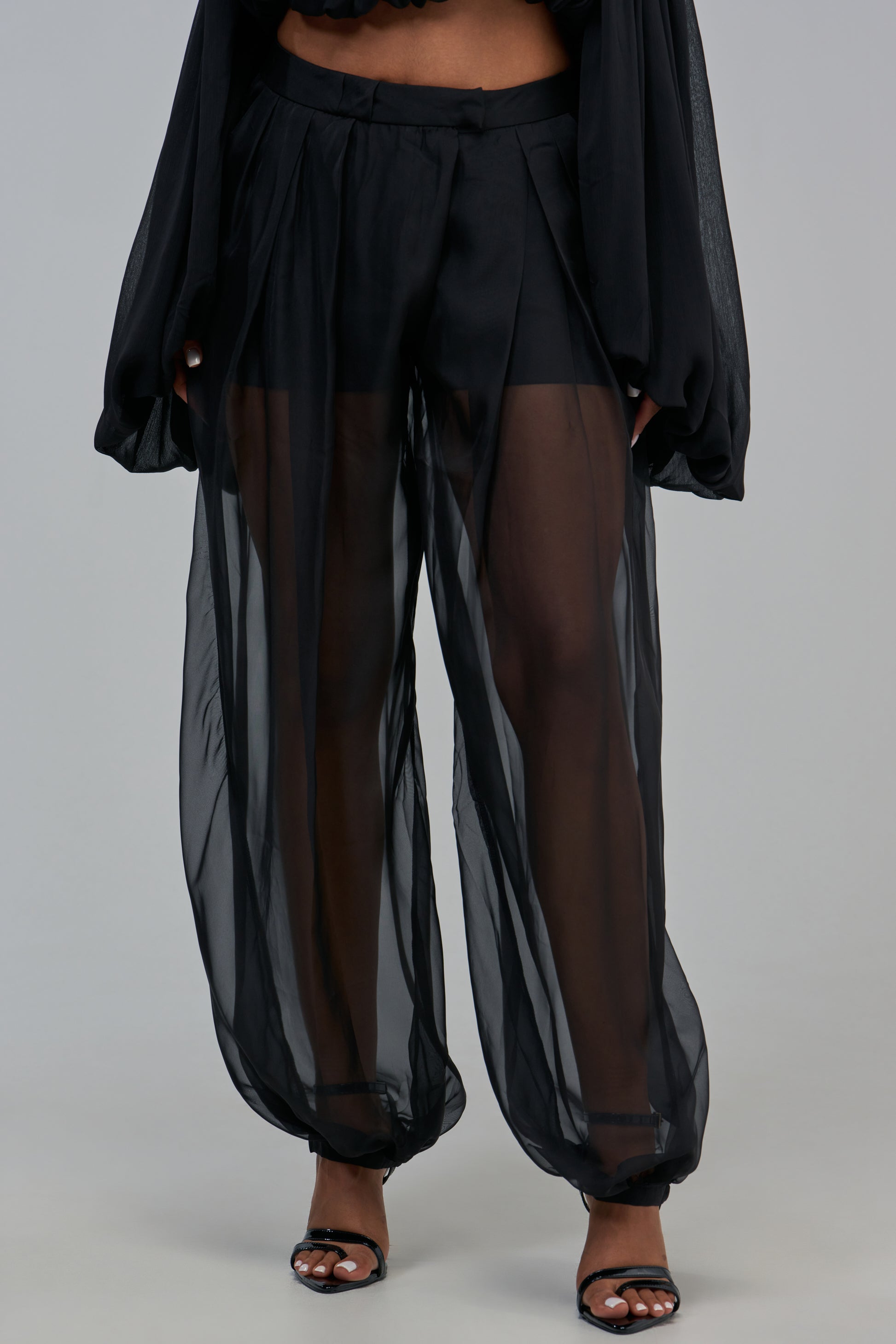SAMMY SHEER BALLOON TROUSER in black, featuring a high-waisted, wide-leg balloon silhouette made of sheer, pleated fabric with a tailored waistband and cuffed ankles.