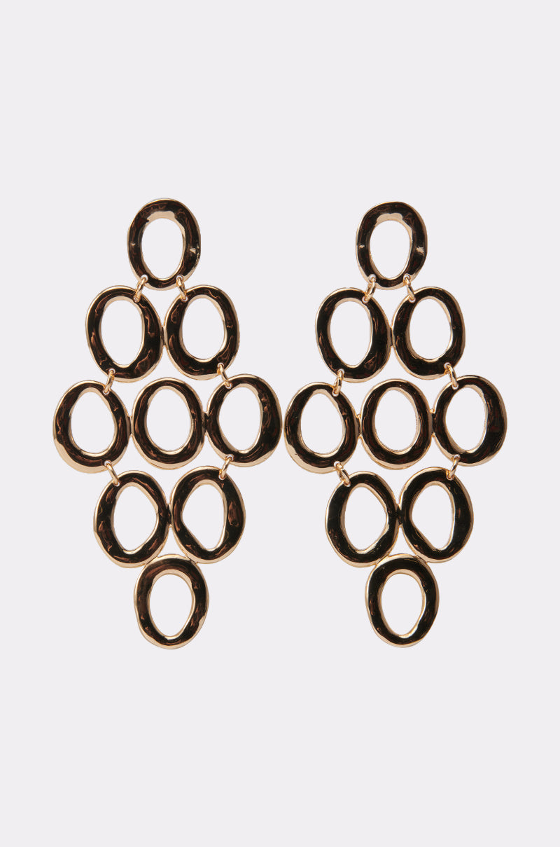 The OUTTA TOWN EARRING features gold-tone geometric drops with interlocking oval loops in a diamond shape, shown on a plain white background—a bold statement accessory for any outfit. 2