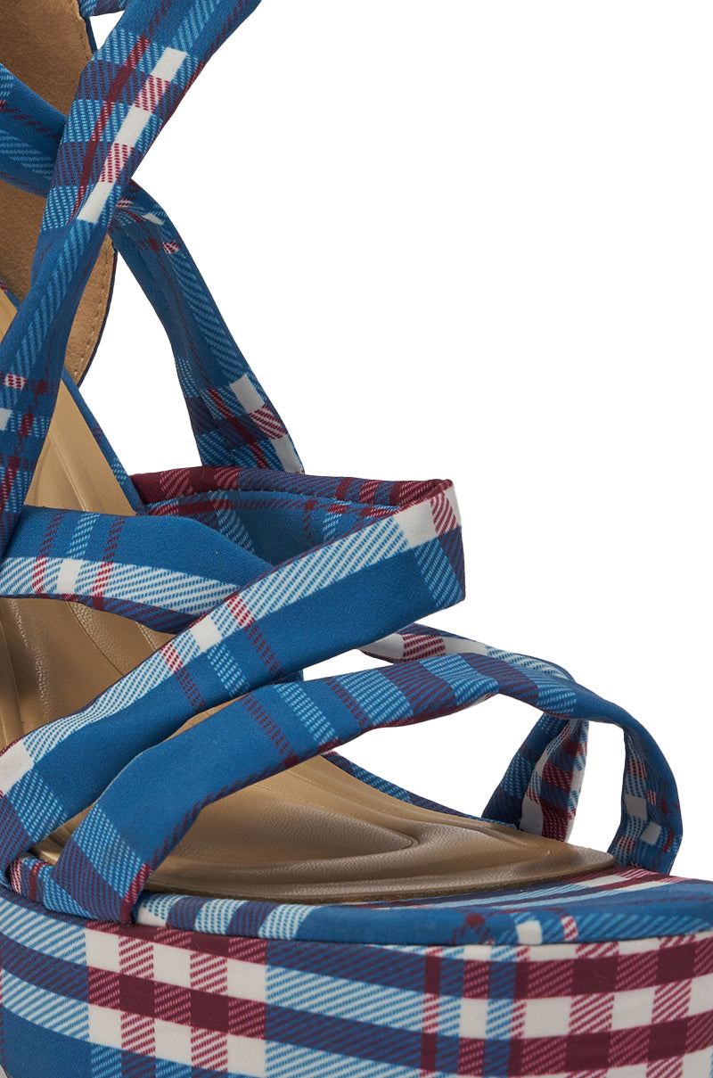 Close-up of the AZALEA WANG JEMISHA BLUE PLAID PRINT PLATFORM STRAPPY SANDAL, featuring blue, red, and white plaid straps, a matching plaid platform sole, crisscross lace-up ankle straps, and a bold stiletto heel. 6