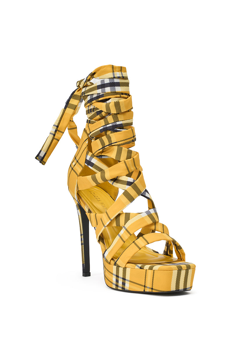 The AZALEA WANG JEMISHA YELLOW PLAID PLATFORM LACE UP SANDAL features a yellow, black, and white plaid pattern, multiple crisscross straps, an ankle tie, a platform sole, and a bold stiletto heel. 4