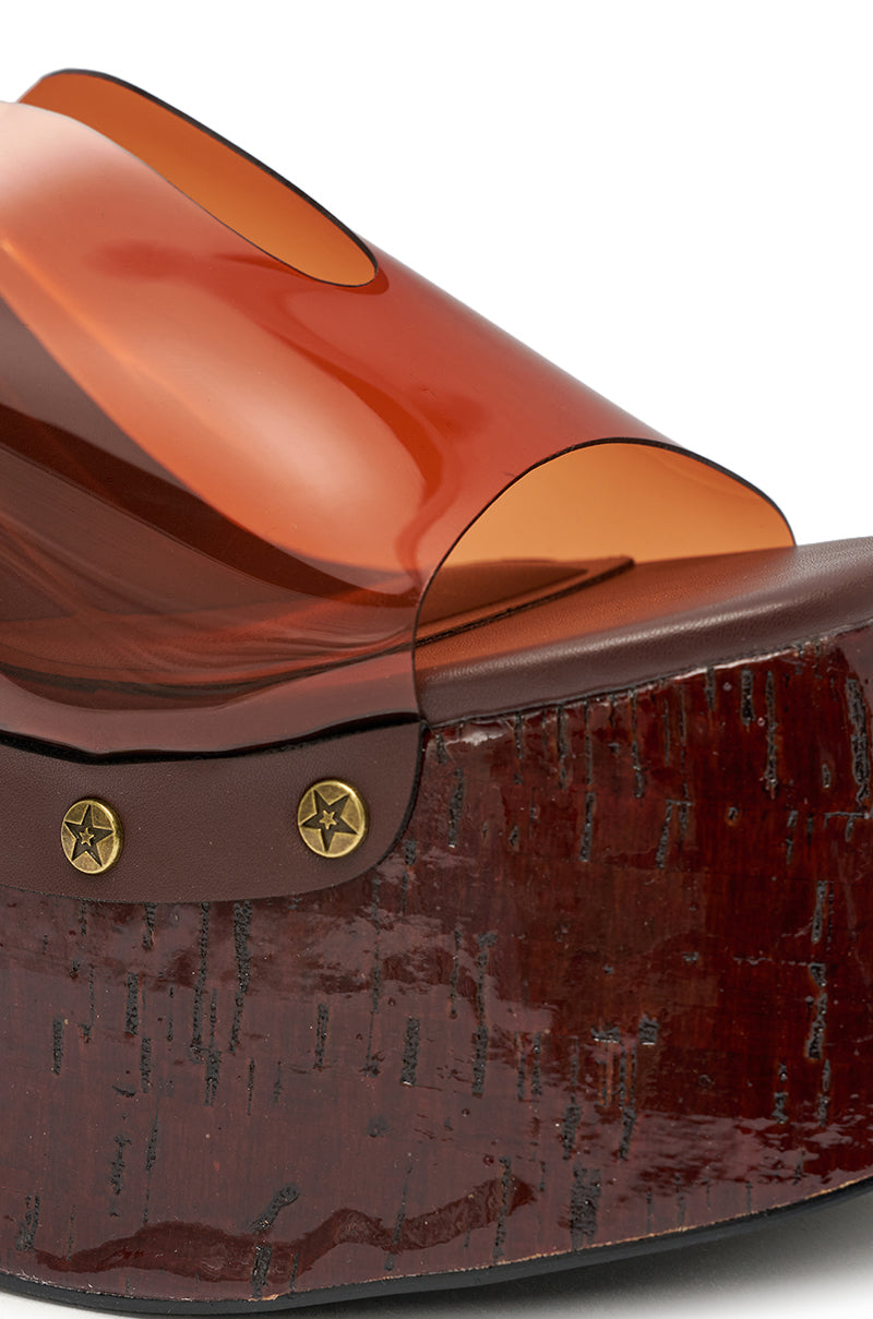 Close-up of the AZALEA WANG JENZA CHOCOLATE WEDGE, featuring a glossy chocolate wood-inspired chunky platform, brass star studs, and a transparent orange upper strap. 8
