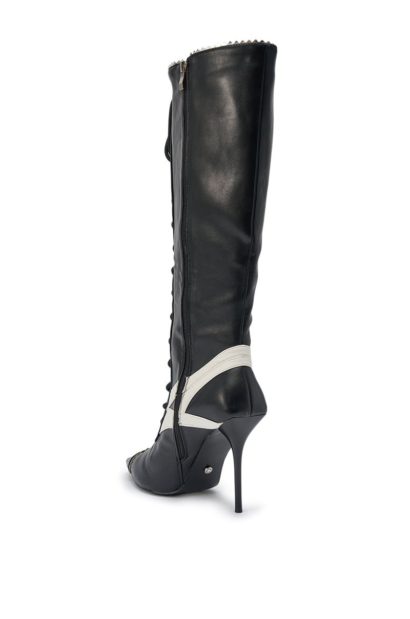 The AZALEA WANG JETER BLACK SPORTY STILETTO BOOT features black faux leather, a knee-high silhouette, pointed toe, front laces, and a white ankle strap detail, displayed from a rear side angle. 6