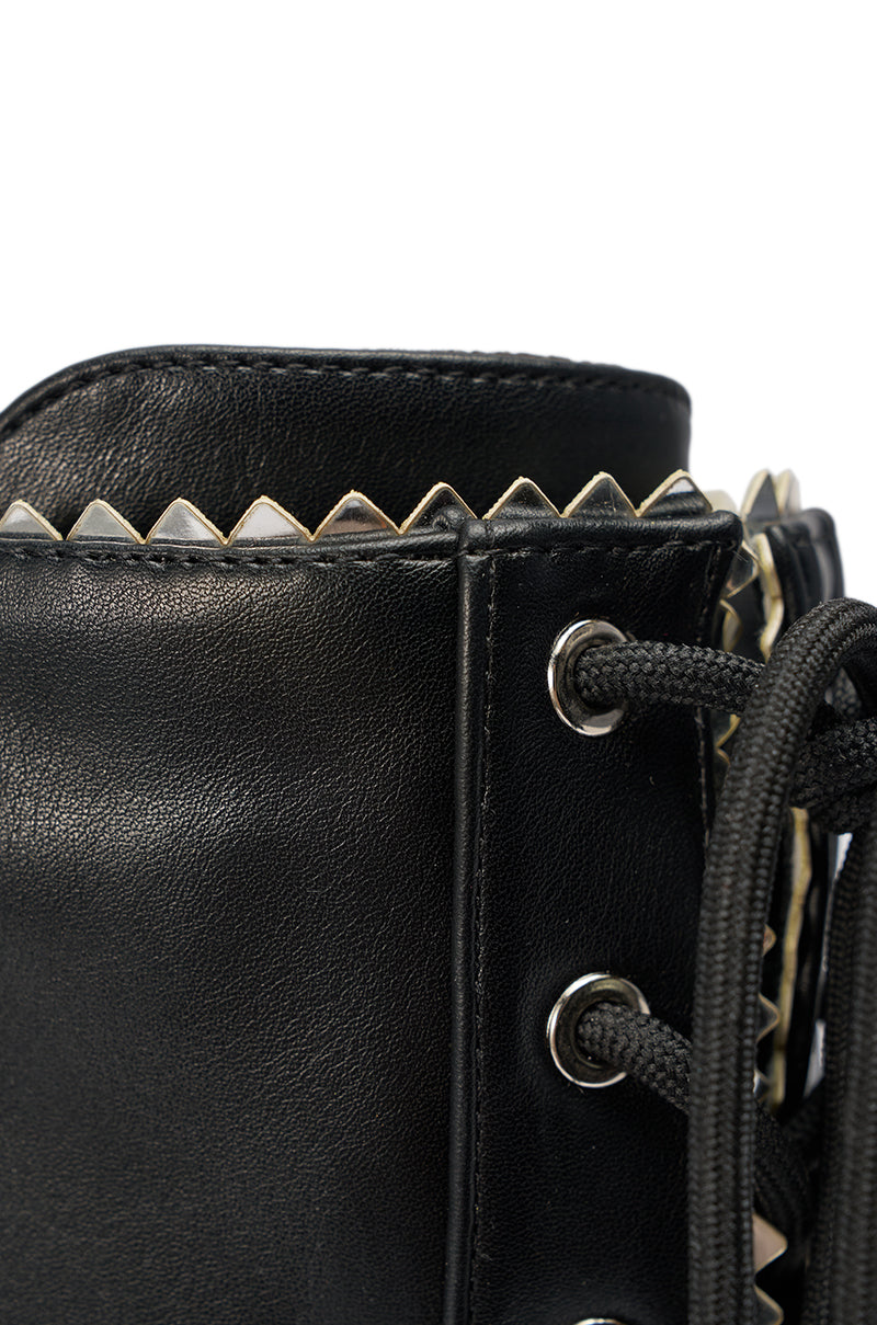Close-up of the AZALEA WANG JETER BLACK SPORTY STILETO BOOT featuring black faux leather, silver zigzag metal trim on the top edge, black laces, and metal eyelets. 7