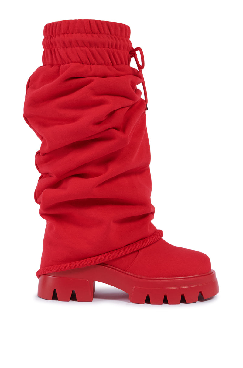 The AZALEA WANG JETSETTER RED BOOT is a striking red oversized boot with a slouchy, sweatpant-inspired design and a chunky platform lug sole. It features a gathered elastic top and drawstring detail, creating a bold and eye-catching silhouette that blends fashion-forward elements with sturdy functionality.