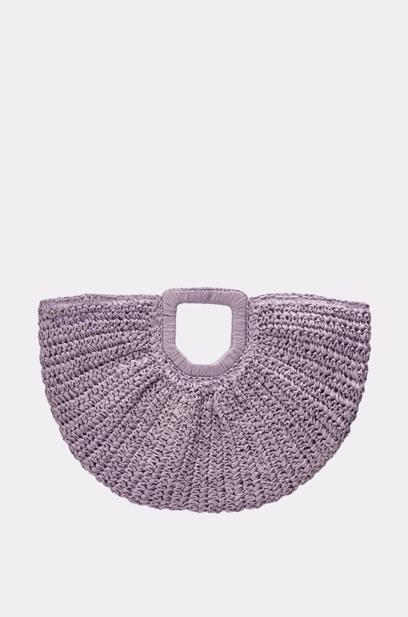 The CATCHING FLIGHT RAFFIA CLUTCH is a lavender, semi-circular woven straw tote with a square handle, shown against a plain white background. 1