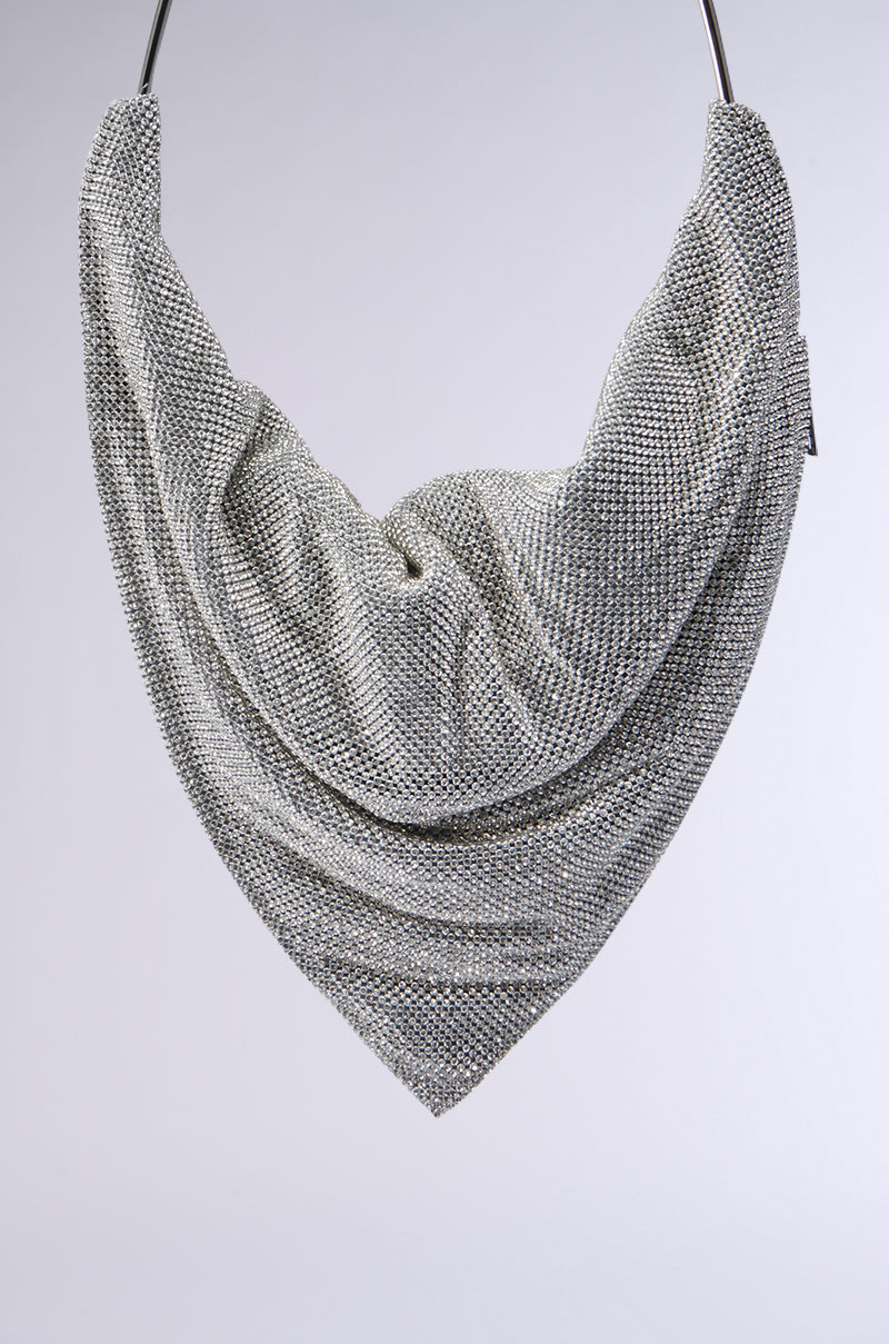 A textured gray scarf with a metallic sheen is elegantly draped in a triangular shape against a light gray background. Nearby, the IM IT LUXE RHINESTONE BAG glimmers subtly, enhancing the soft fabric's folds and intricate patterns with its sparkle. 4