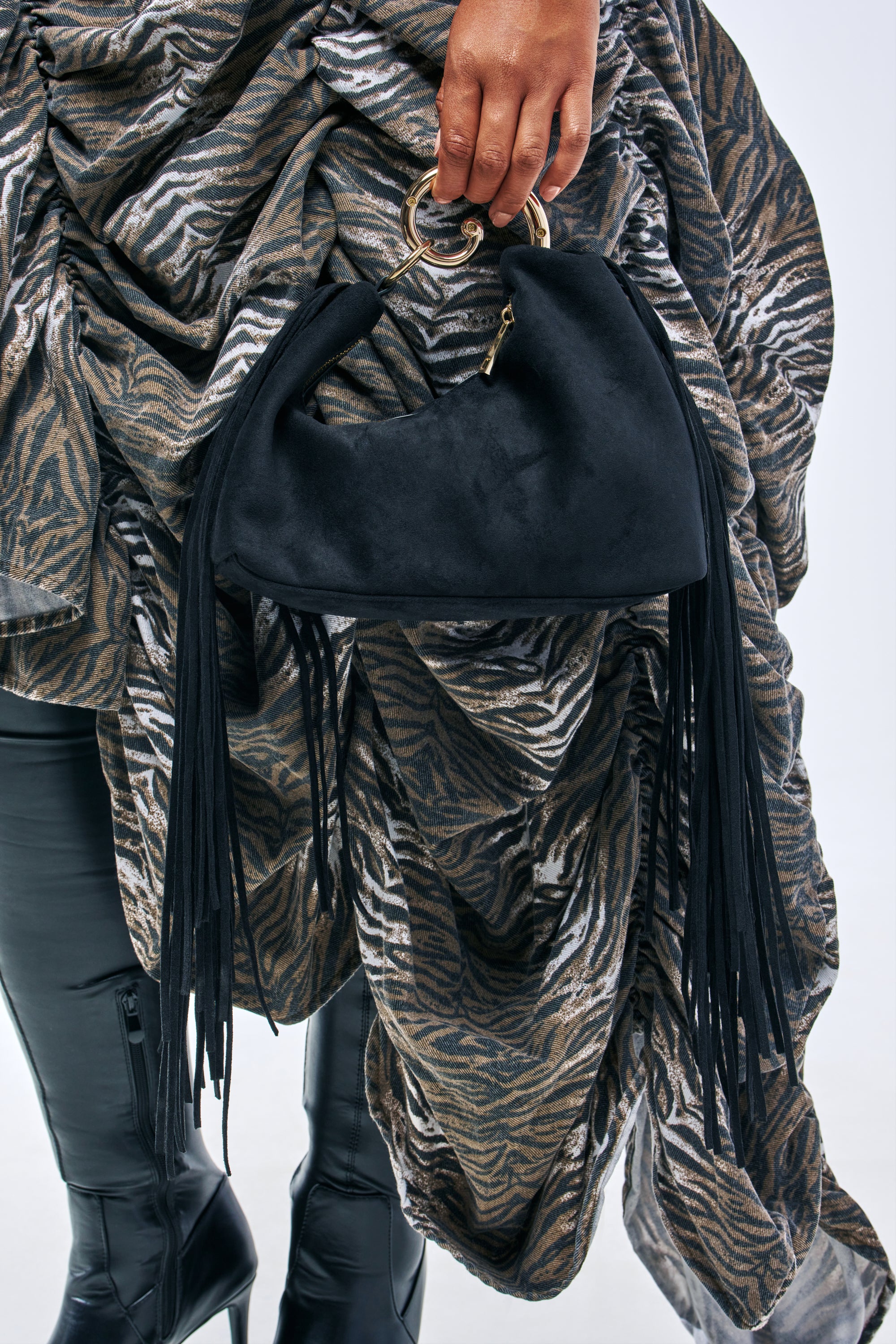 A black suede FRINGE FOR DAYS SUEDE BAG with fringe detail, suspended from a gold ring handle.
