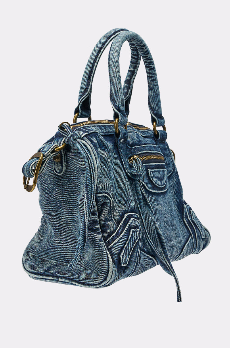 Introducing the IM THAT GIRL DISTRESSED PURSE—a slouchy moto bag crafted from blue denim with gold-tone hardware, multiple pockets, and double handles, showcased on a simple light background. 4