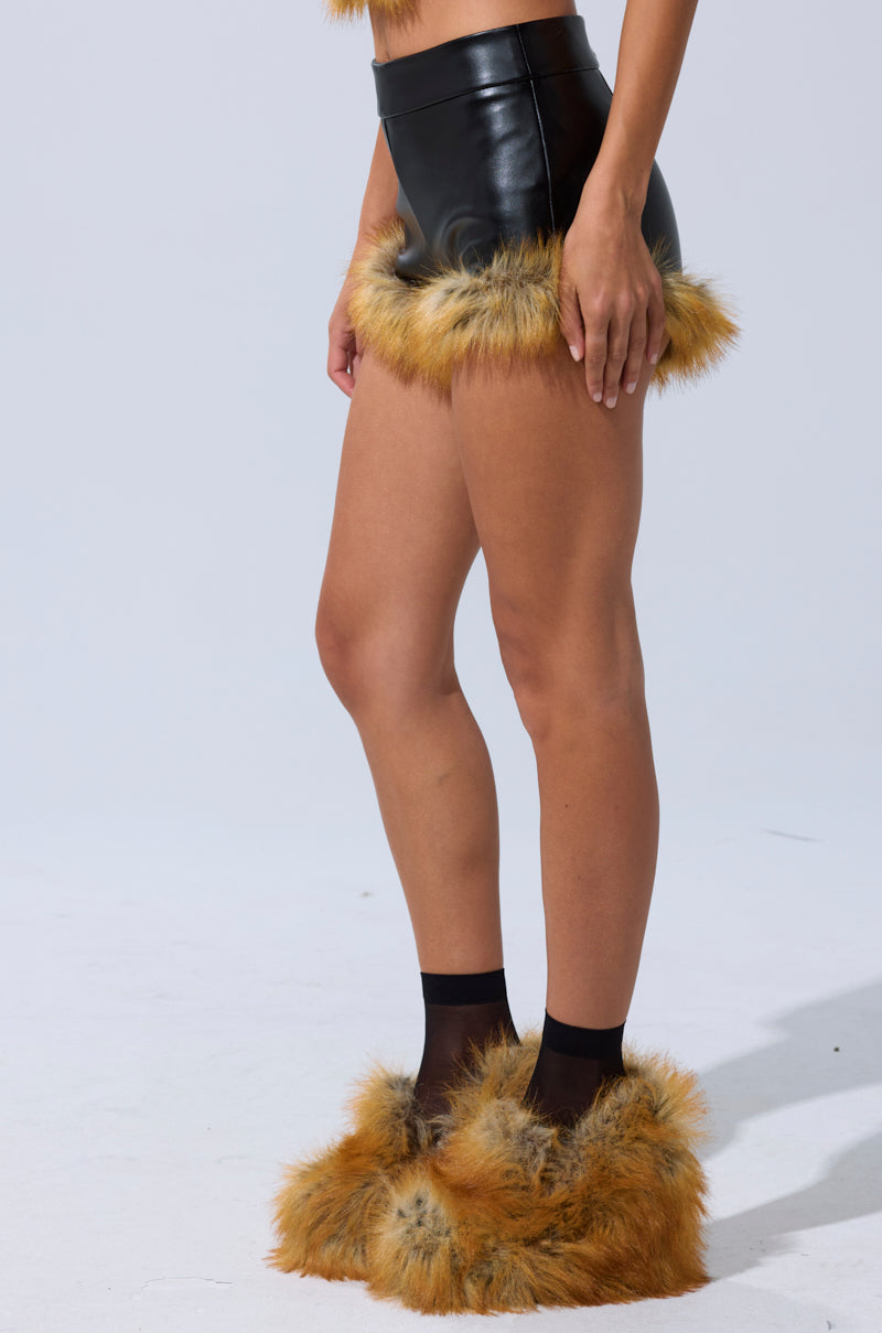 A person wears the DONT TOUCH SHORT WITH FUR TRIM, paired with black sheer socks and fluffy light brown fur slippers, standing against a plain light background. 4