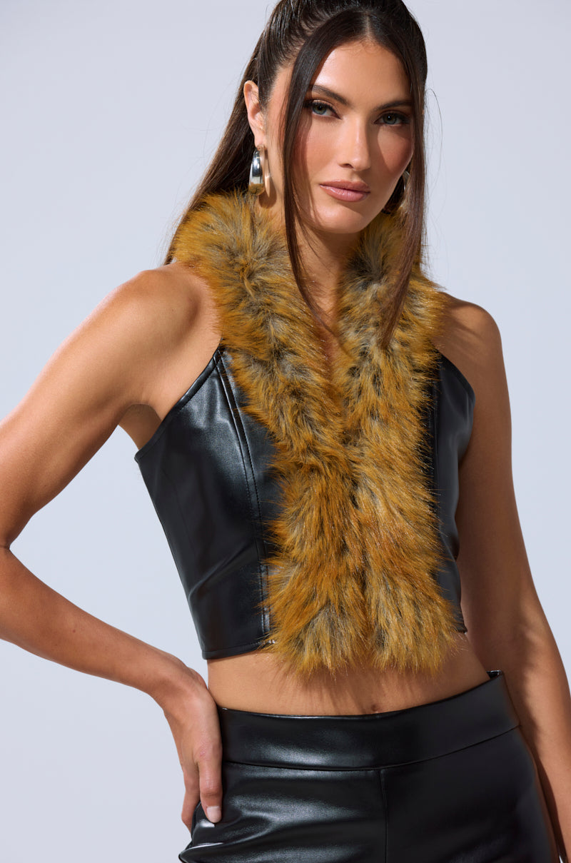 A woman poses confidently in the DONT TOUCH FUR BRALETTE and black pants, accessorized with large hoop earrings and a yellow-brown fur-trimmed scarf. She has long brown hair. 0