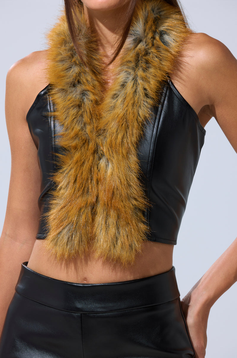 A woman wears the DONT TOUCH FUR BRALETTE in black faux leather, paired with pants and a multicolored faux fur scarf draped around her neck. 8