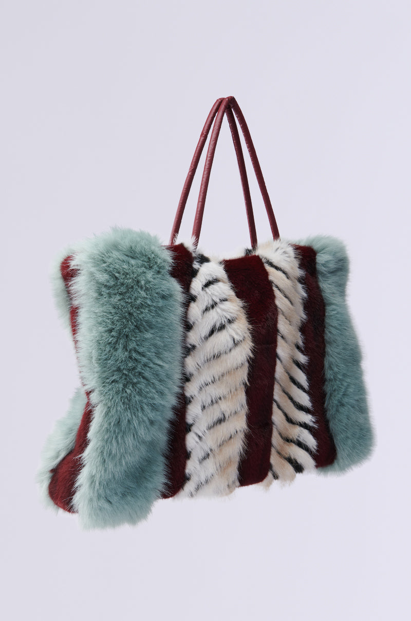 The "HAVE IT ALL FAUX FUR TOTE" features a chic color block design with teal, burgundy, and white faux fur sections. Its oversized, rectangular shape and two thin handles give it a plush, luxurious look perfect for any fashionista. 6