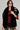 A woman with long hair wearing sunglasses strikes a pose in a stylish ensemble: a black and white oversized fur coat layered over a red sports jersey. She completes the look with black lace shorts and adds an elegant touch with the F*CK IT FAUX FUR SCARF, standing against a plain backdrop.
