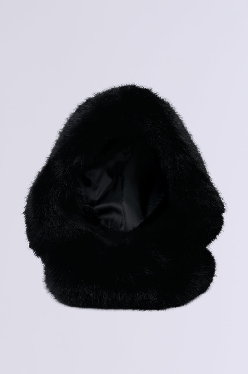 The IM THE ONE FAUX FUR HOOD is oversized, black, and has a soft, fluffy texture for warmth and style. Designed as a perfect winter accessory, its visible inside lining adds luxury. Set against a plain grey background. 2