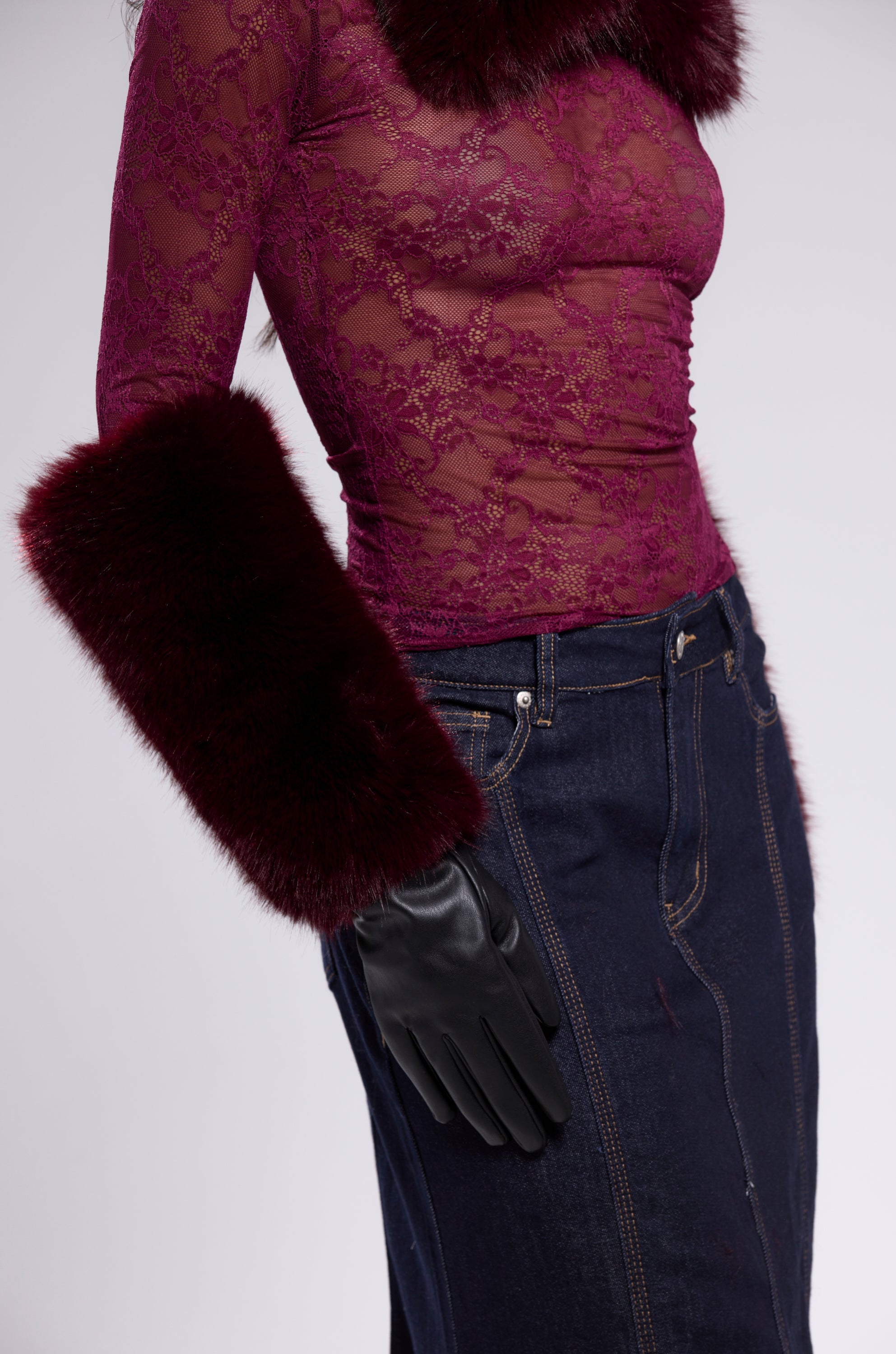 A person wears the ALAIA FAUX FUR GLOVES with a sheer burgundy lace top featuring faux fur trim, paired with a dark denim skirt. The image is cropped from shoulders to mid-thigh. 6