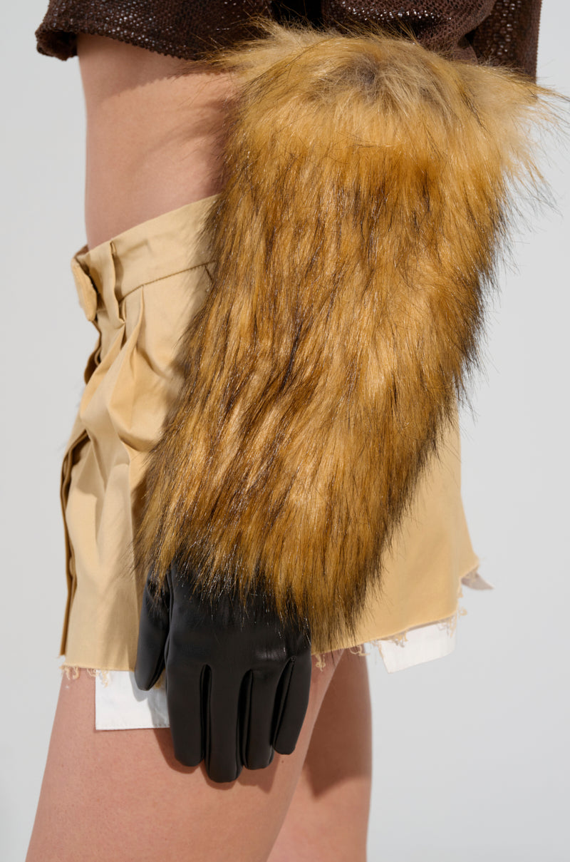 A model stands wearing beige shorts and a brown top, complemented by a furry arm piece, highlighting the GRACELLE EXTENDED FAUX FUR GLOVES as the perfect winter accessory. 2