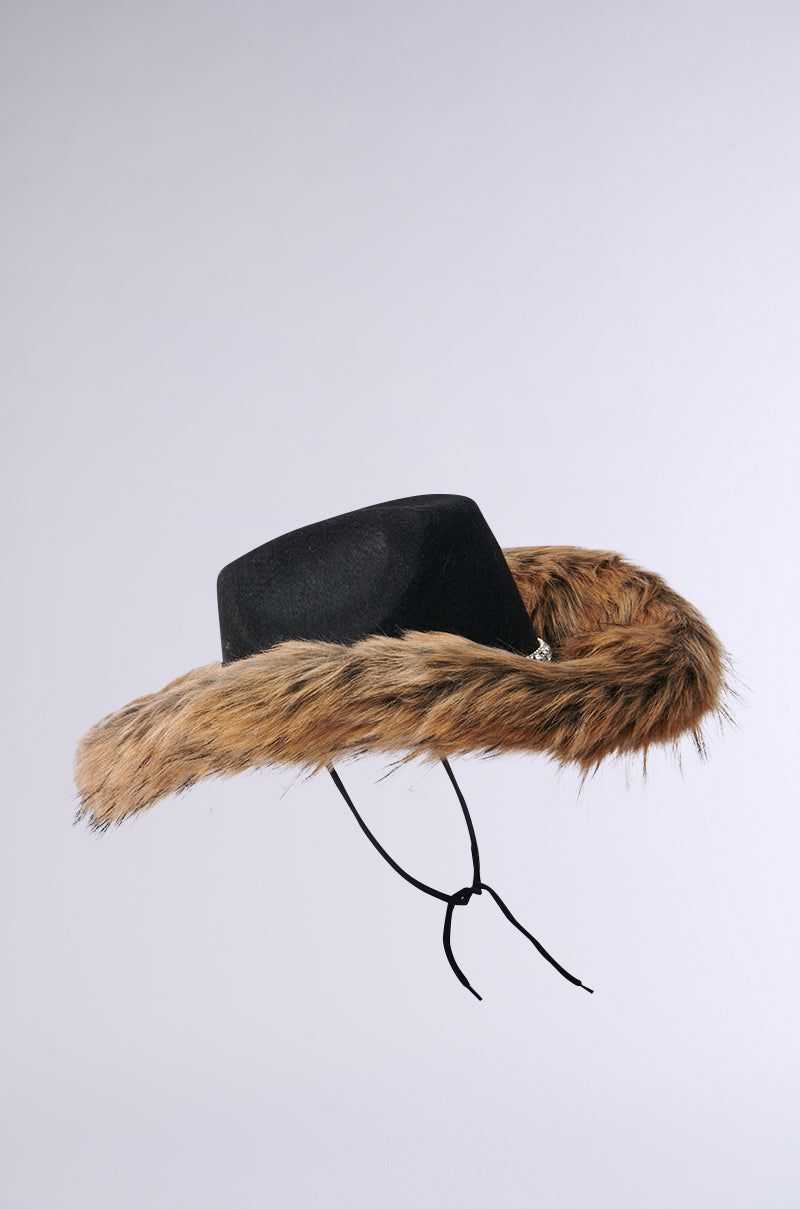 The IS THIS EXTRA FUR COWBOY HAT features a black tricorn design with plush faux fur trim and sparkling rhinestone accents. It stands out against a light gray background, adorned with elegant black strings hanging beneath it.