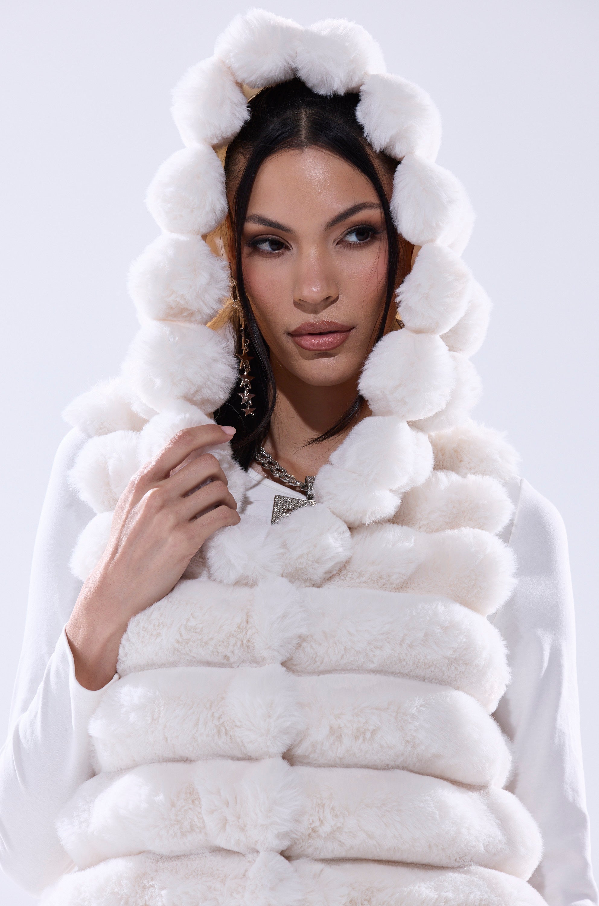 A woman wearing the POPPY FAUX FUR HOODED VEST, a cozy white layer perfect for winter style.