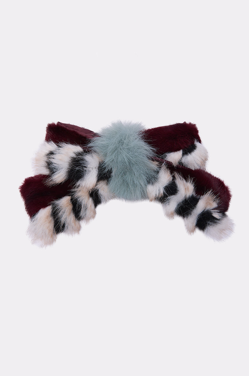 The HAVE IT ALL FAUX FUR HAIR CLIP is an oversized bow accessory in burgundy, light blue, white, and black faux fur with a soft blue pom-pom center and striped loop accents, shown on a plain white background. 3