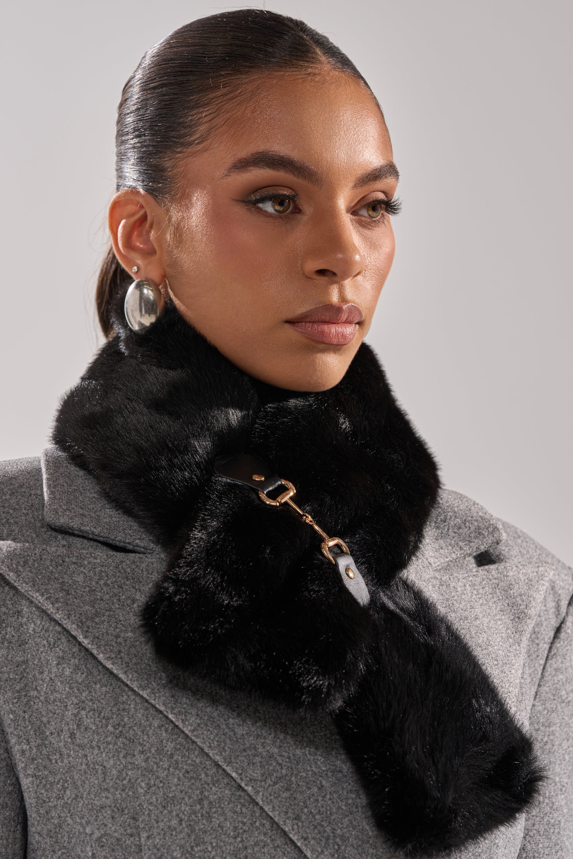 A woman showcases effortless style wearing the HORSEBIT FAUX FUR SCARF, a cozy and chic accessory. 0