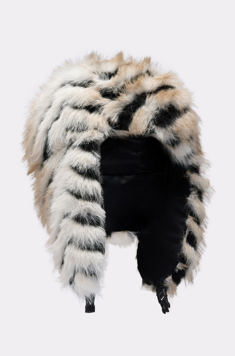 The PORTIA AVIATOR HAT is a cozy, reversible hat with ear flaps, striped white, black, and light brown faux fur, a soft black lining, and a secure chin strap buckle for warmth and style. 11