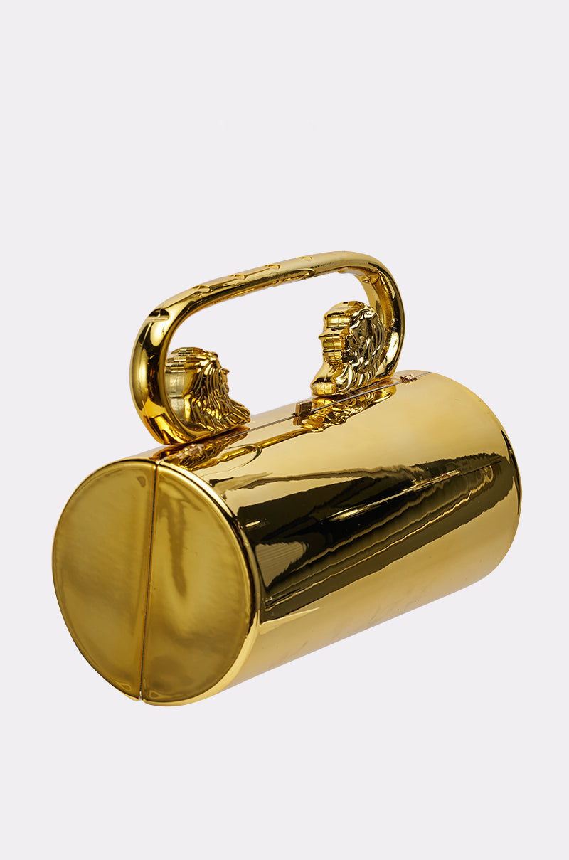 The LETS GO OUT CLUTCH BAG is a shiny metallic gold cylindrical evening purse, featuring a handle with two sculpted lion heads facing each other, shown against a plain white background. 3