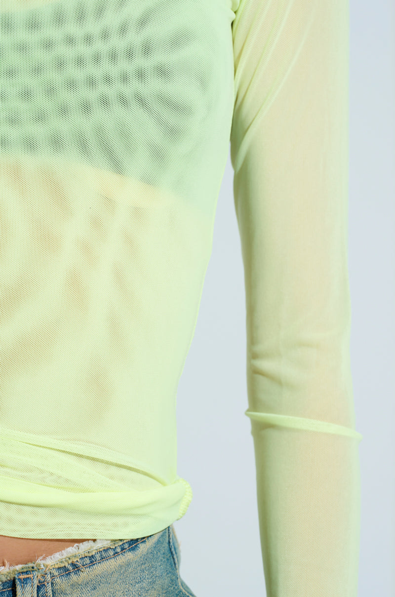 Close-up of someone in the Paxton Sexy Double Lined Mesh Long Sleeve Top, paired with faded denim jeans. The slightly translucent mesh subtly reveals an undershirt, highlighting textures and creating a club-ready outfit. Neon sleeves add flair to this effortlessly stylish look.